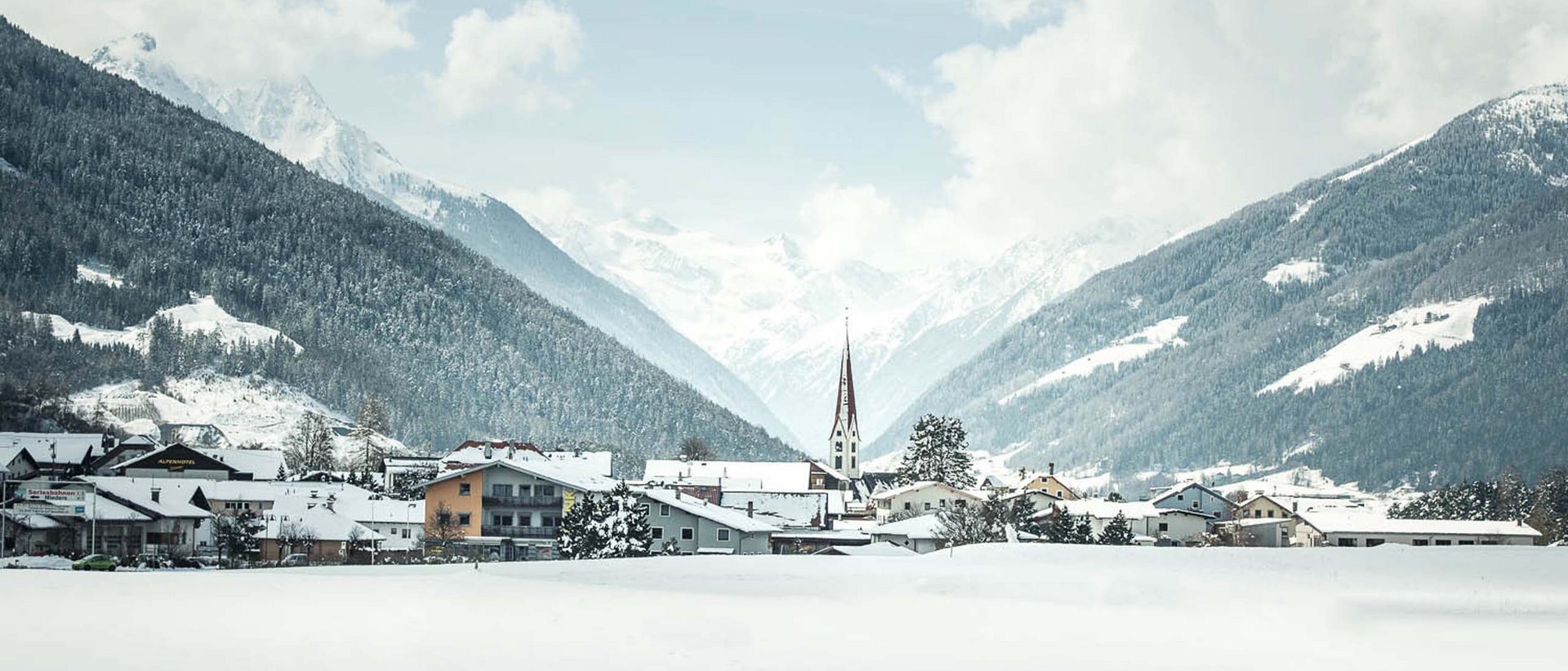Alles, was das Herz begehrt Schneebedecktes Tal mit Dorf und Berggipfeln im Hintergrund