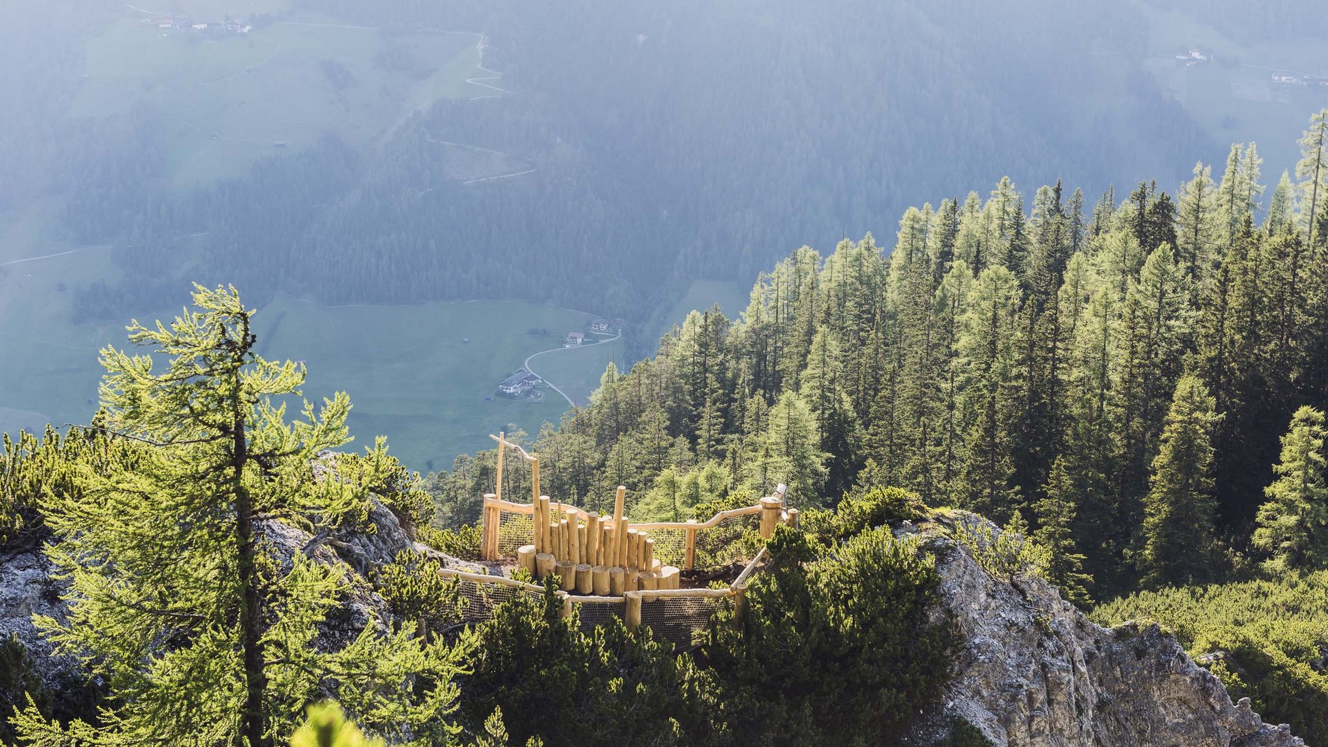 Rund um den Gletscher: Tirol im Sommer Holzspielplatz auf Berggipfel mit Wald und Tal im Hintergrund