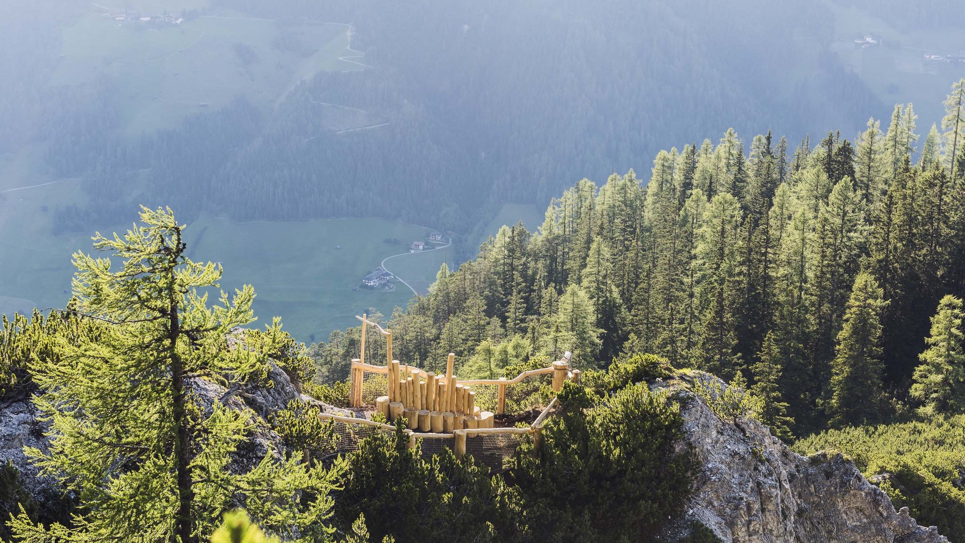 Rund um den Gletscher: Tirol im Sommer Holzspielplatz auf Berggipfel mit Wald und Tal im Hintergrund