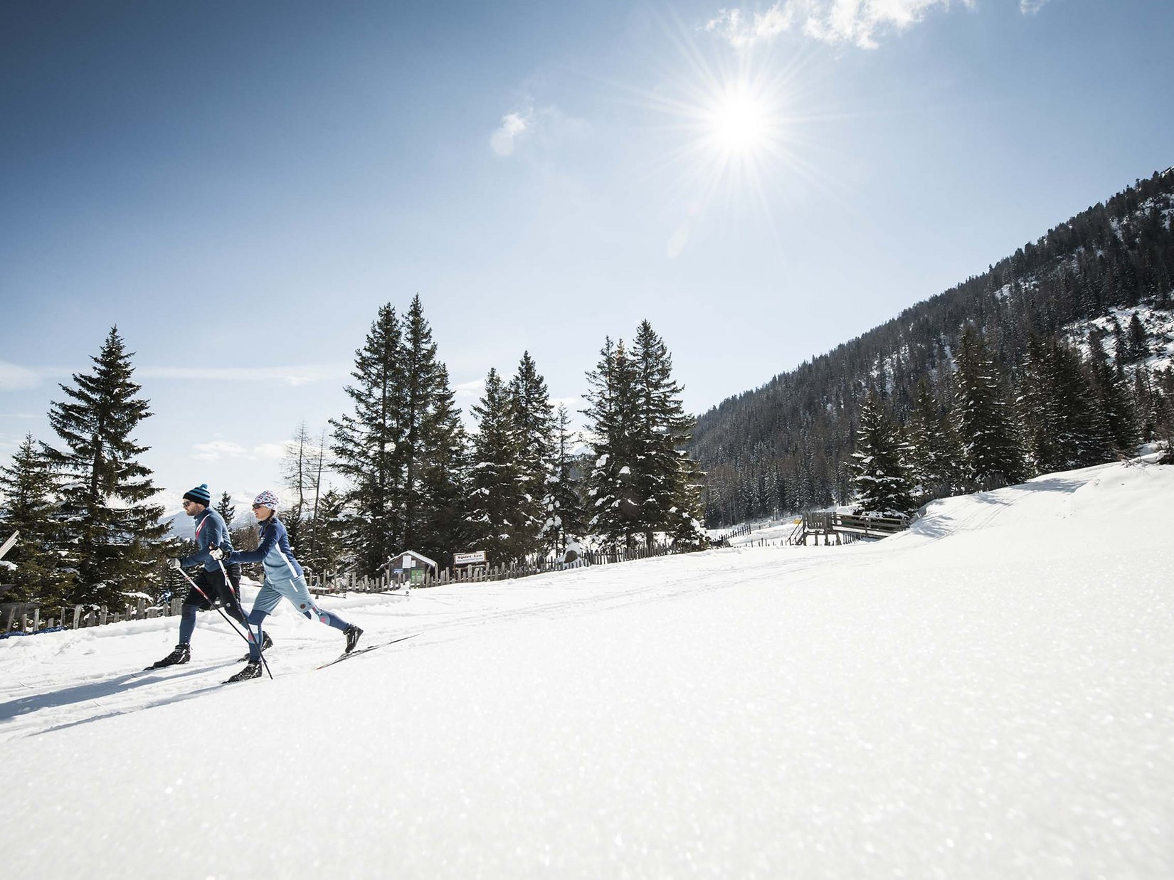 Stubaital: our hotel with a pool Two cross-country skiers in sunny snowy mountain landscape