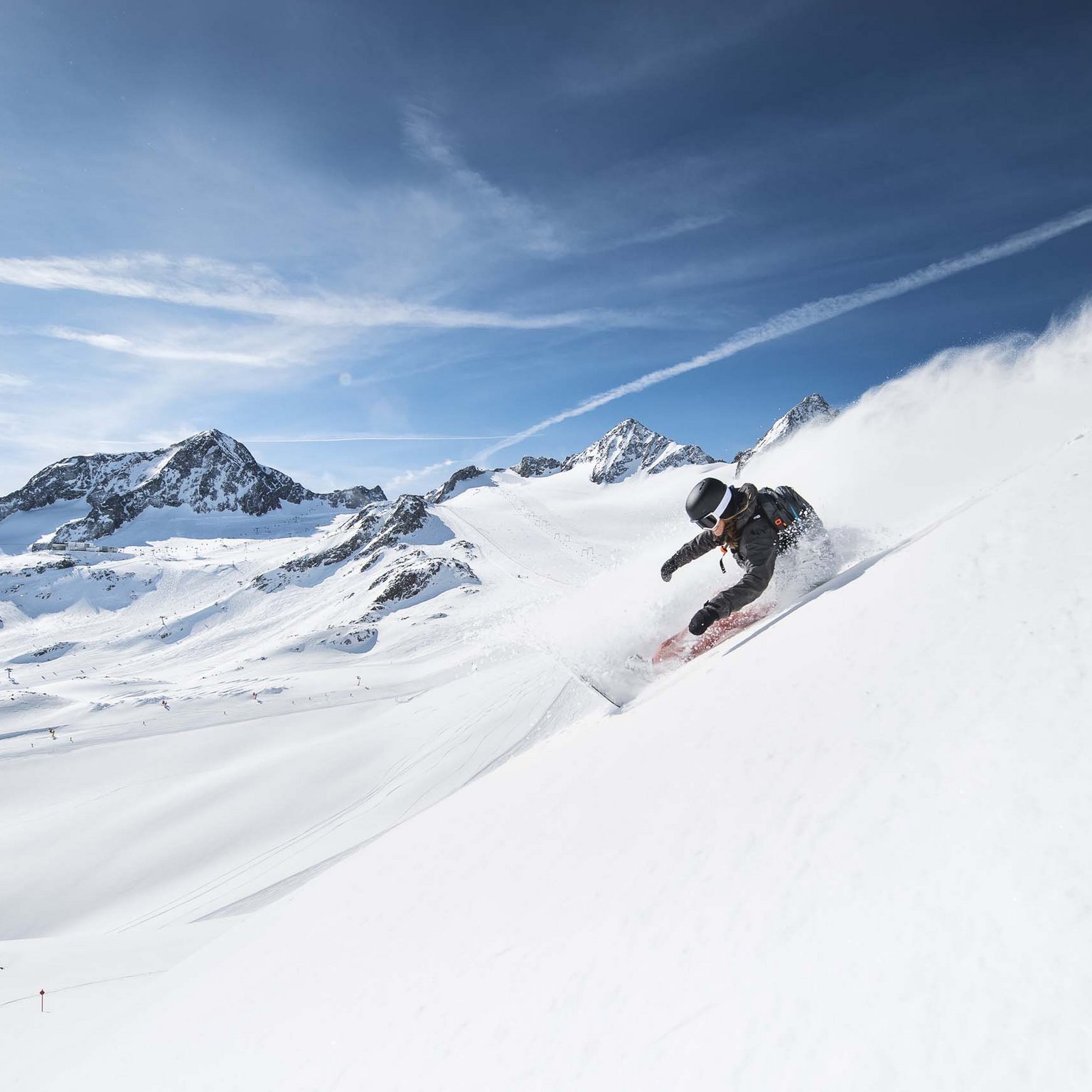 Stubaital: our hotel with a pool Snowboarder riding steep snowy mountain slope in bright daylight