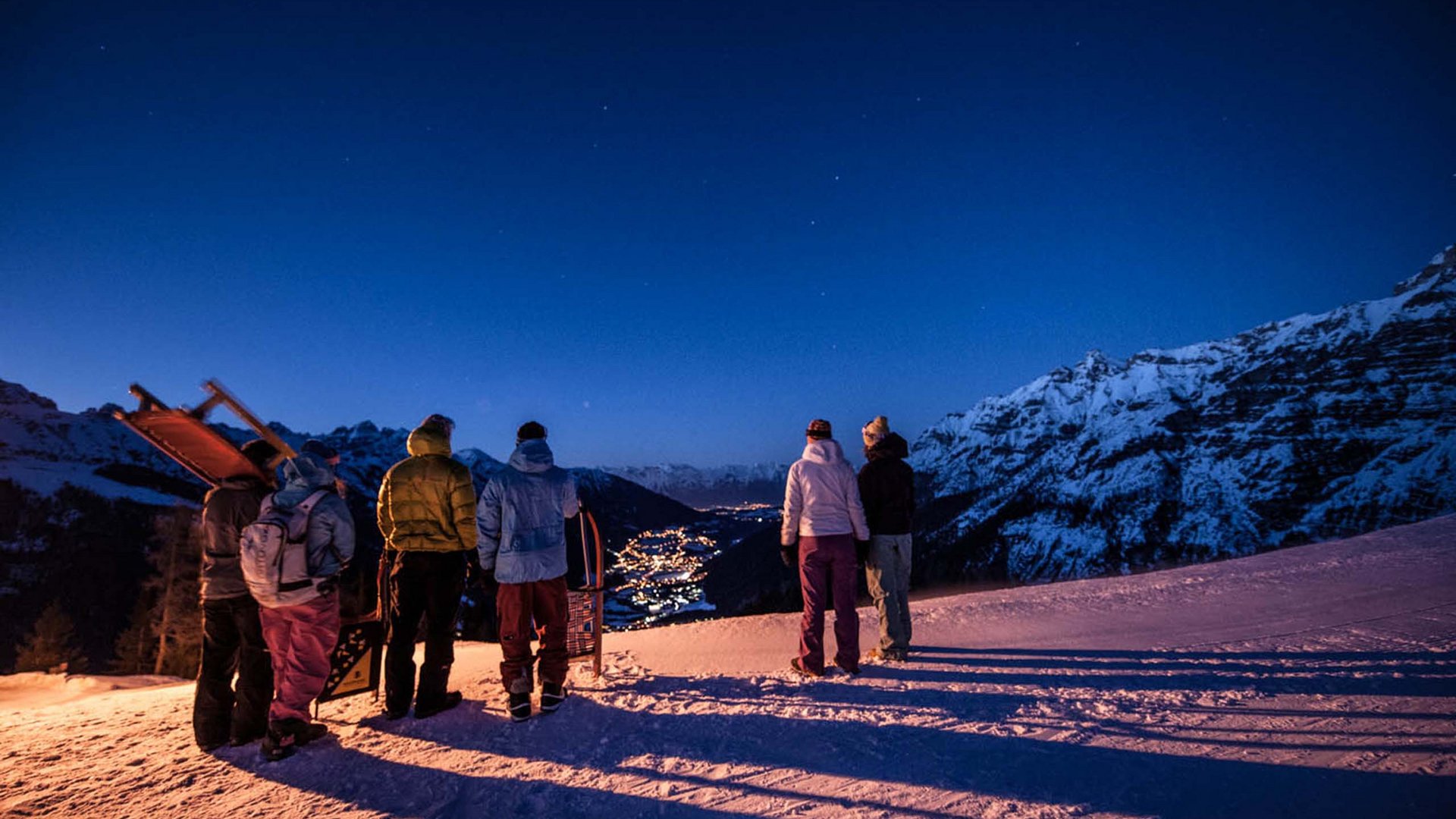 Neustift: the active hotel in Stubaital Group of people with sleds at night in snowy mountain area