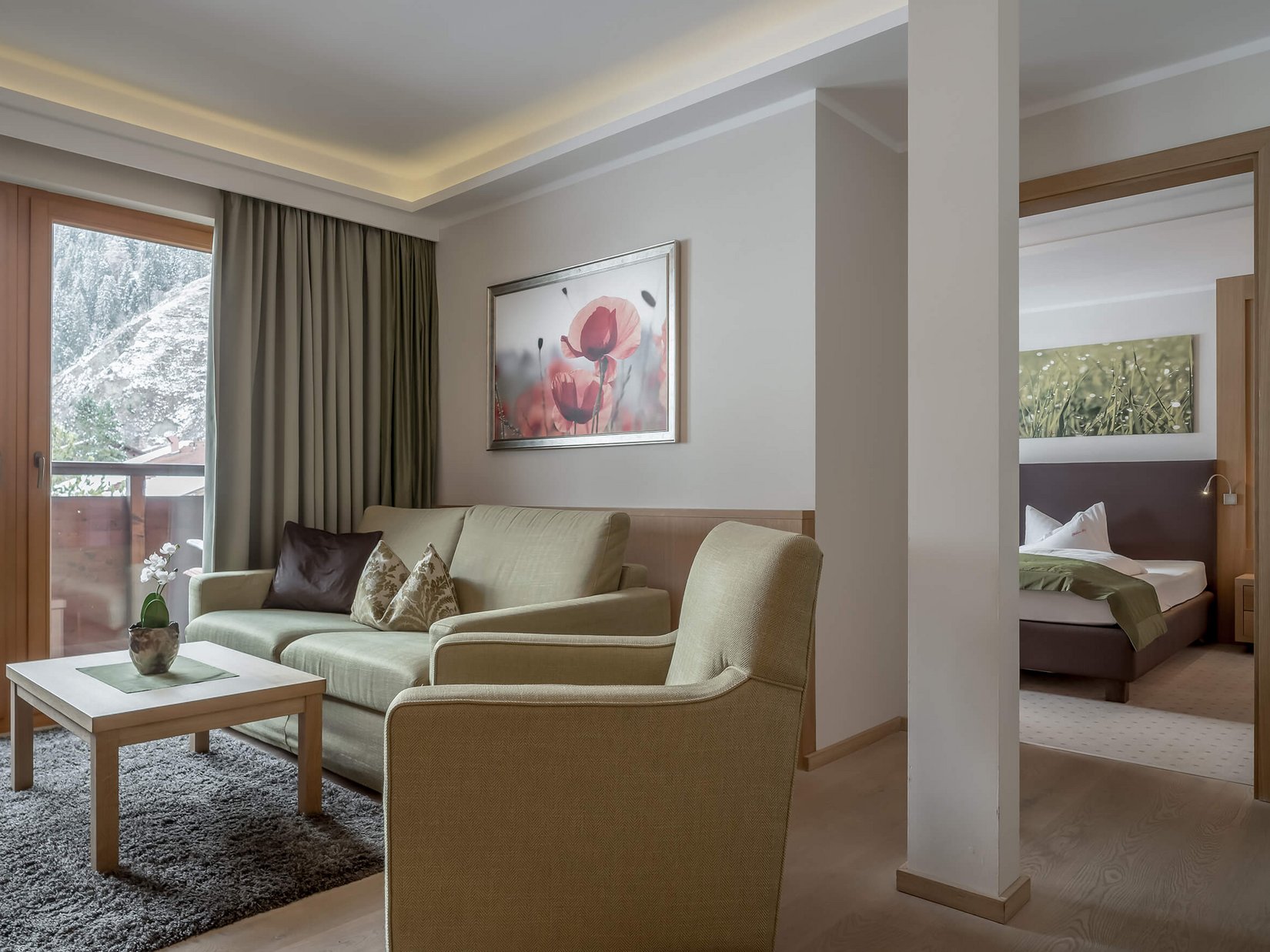 Stubaital: our hotel with a pool Cozy living room with sofa, armchair, bedroom view and balcony with mountain panorama