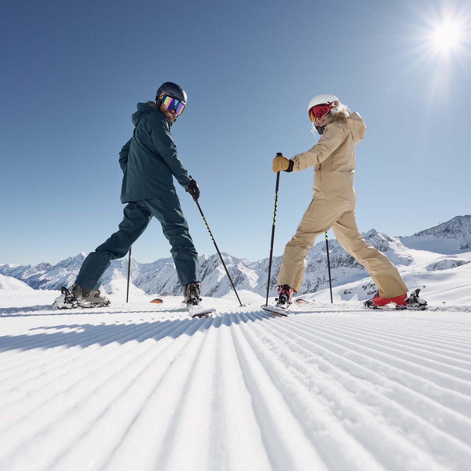 The Stubai Glacier Two skiers on groomed slope under clear sun with mountain views