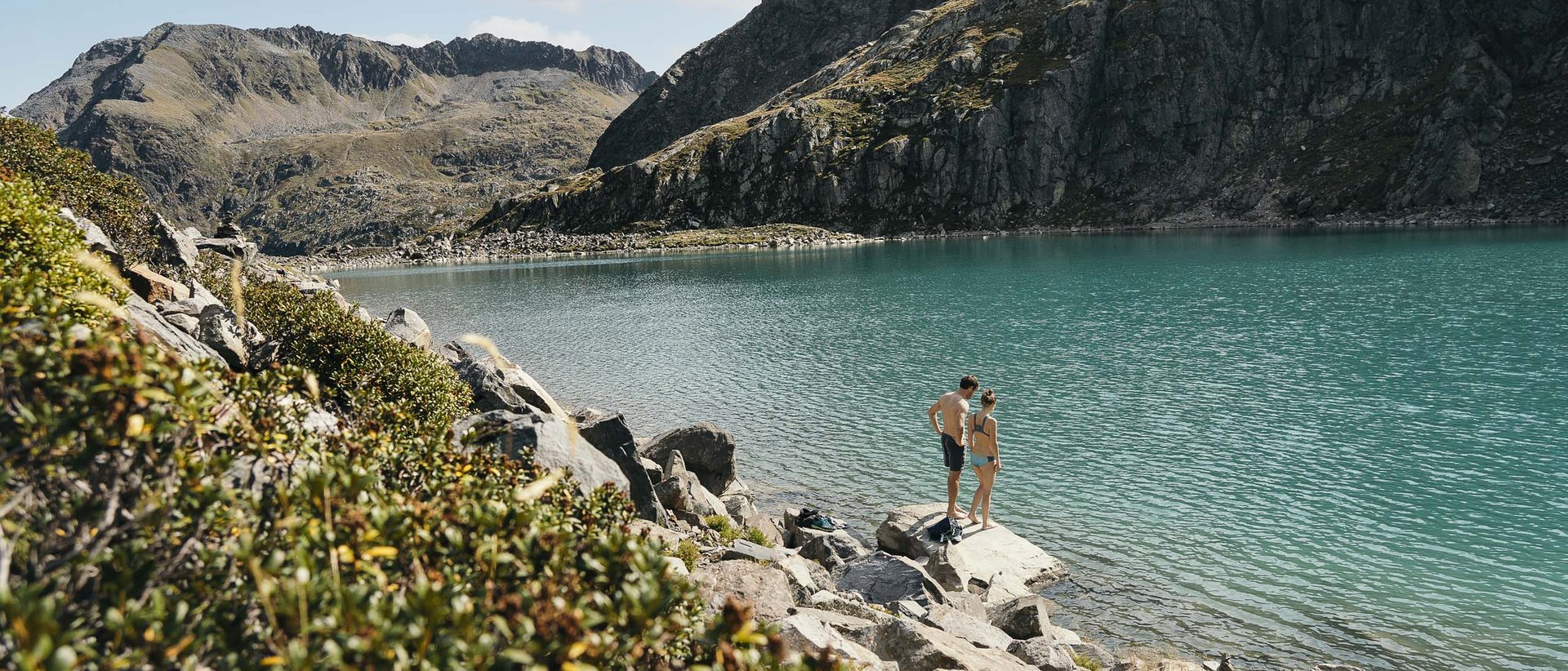 Wanderglück hoch 10 Zwei Menschen stehen am Ufer eines Bergsees mit Felsen und Bergen im Hintergrund