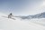 Skifahrer fährt auf schneebedecktem Hang mit Bergen im Hintergrund