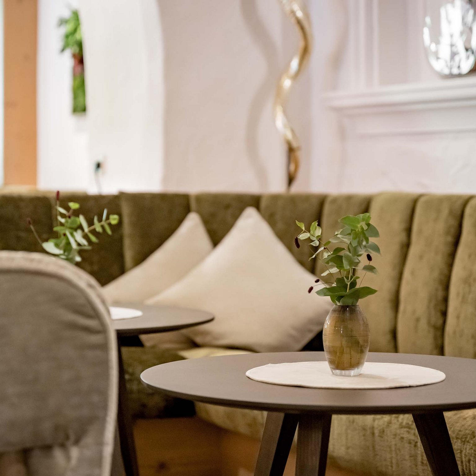 Stornobedingungen Cozy seating area with green sofa, round tables, and vase with green plant