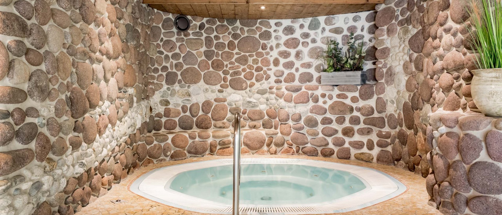 Verbessern Sie Ihr Wohlbefinden! Whirlpool in einem Raum mit Steinwänden und Holzdecke