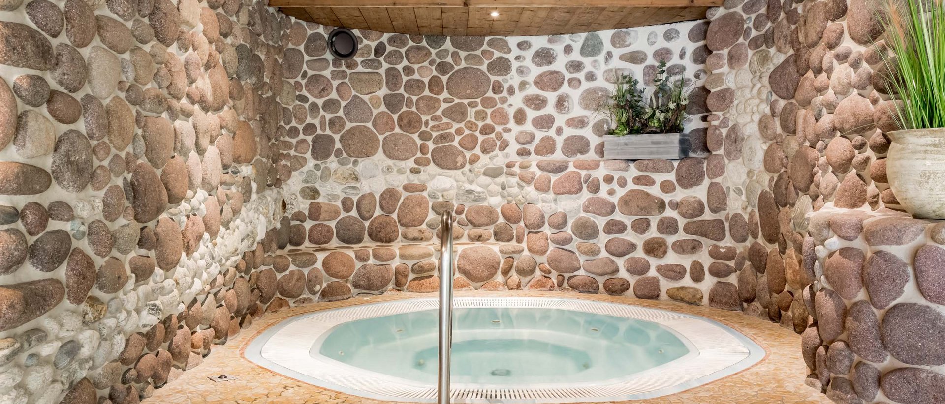 Verbessern Sie Ihr Wohlbefinden! Whirlpool in einem Raum mit Steinwänden und Holzdecke