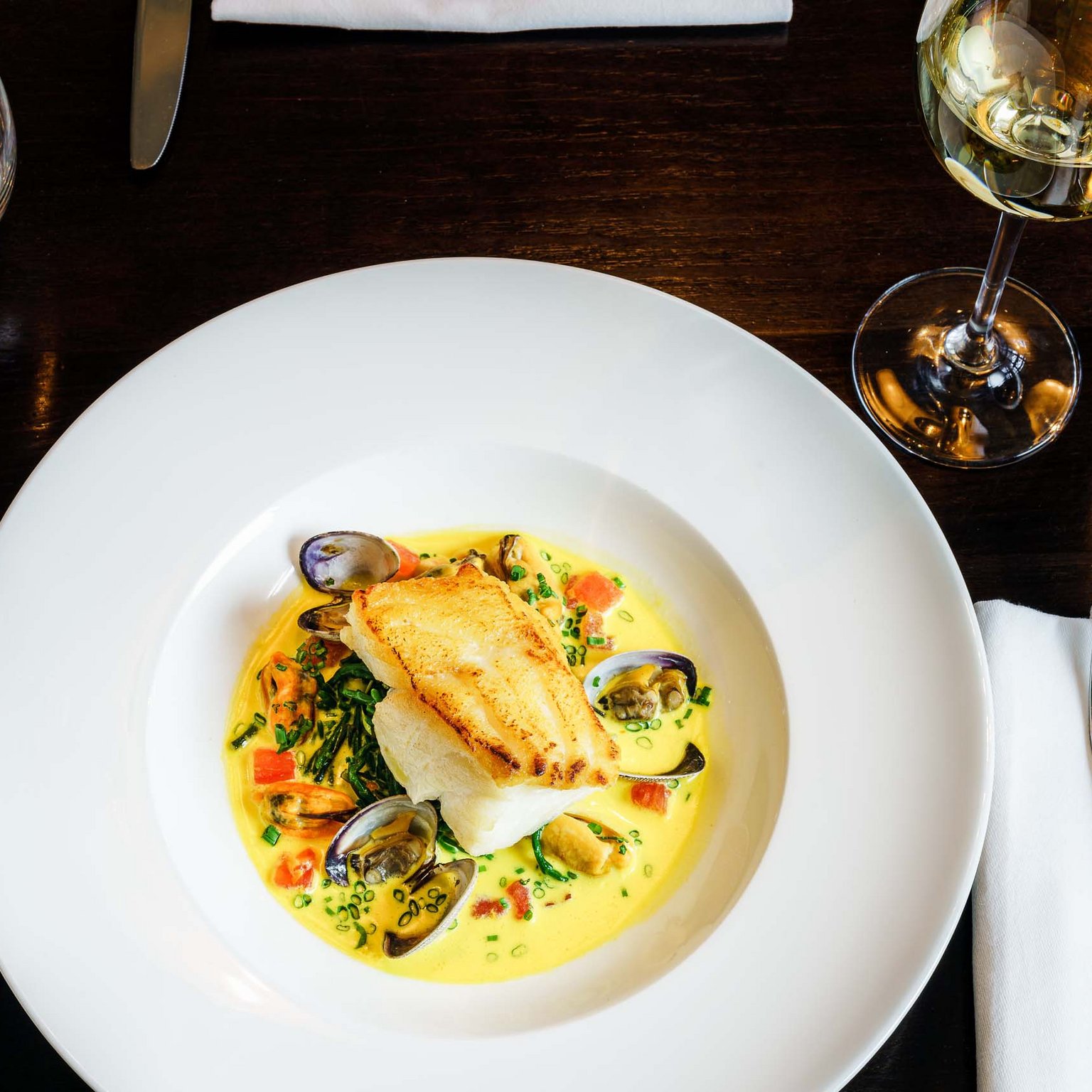 Hotels/Tyrol: 4-star superior holidays Pan-seared fish fillet with clams and creamy sauce on white plate