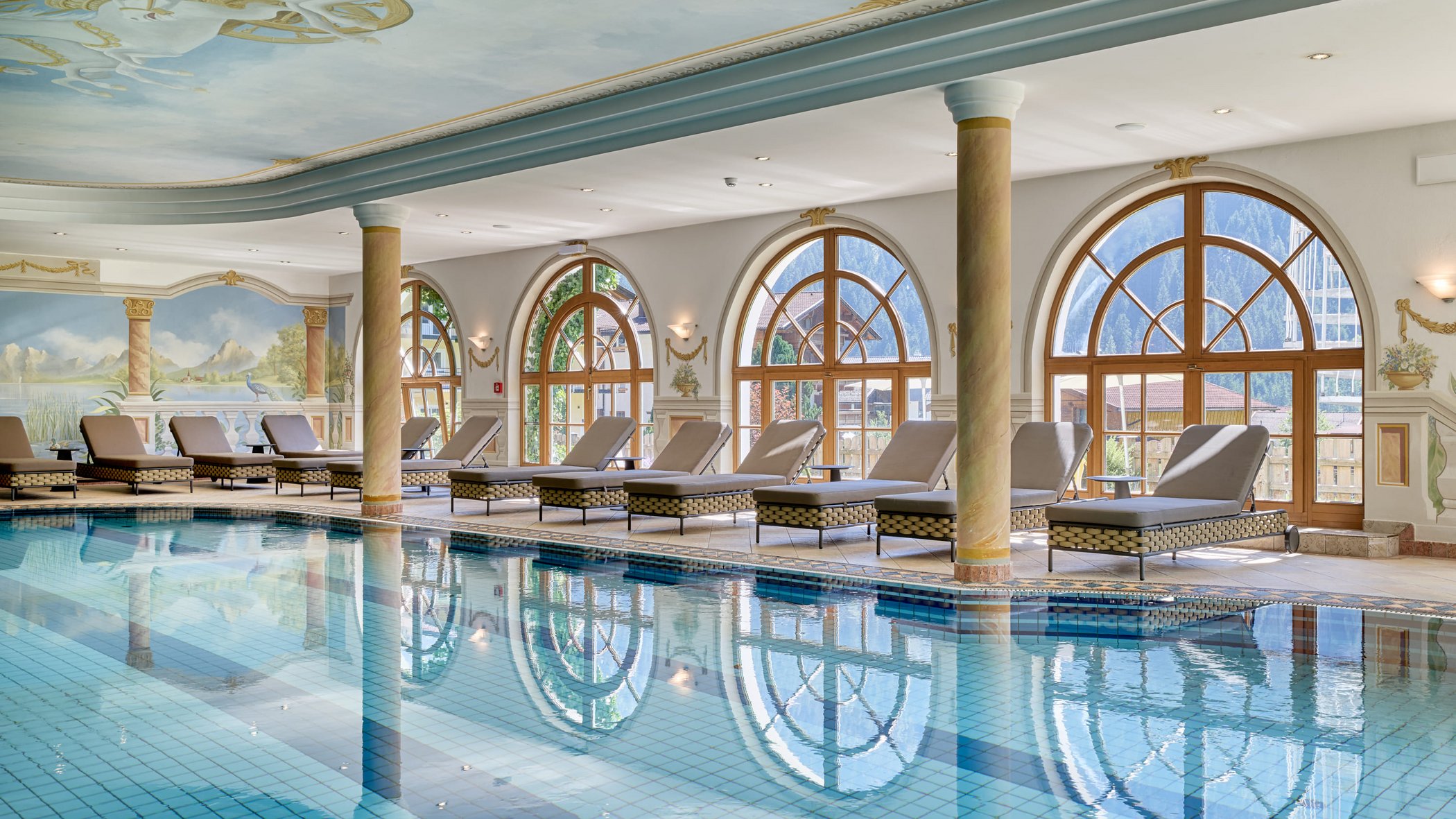 Hof wellness holiday: the Marienbad spa Elegant indoor pool with loungers and large arched windows showing mountain views