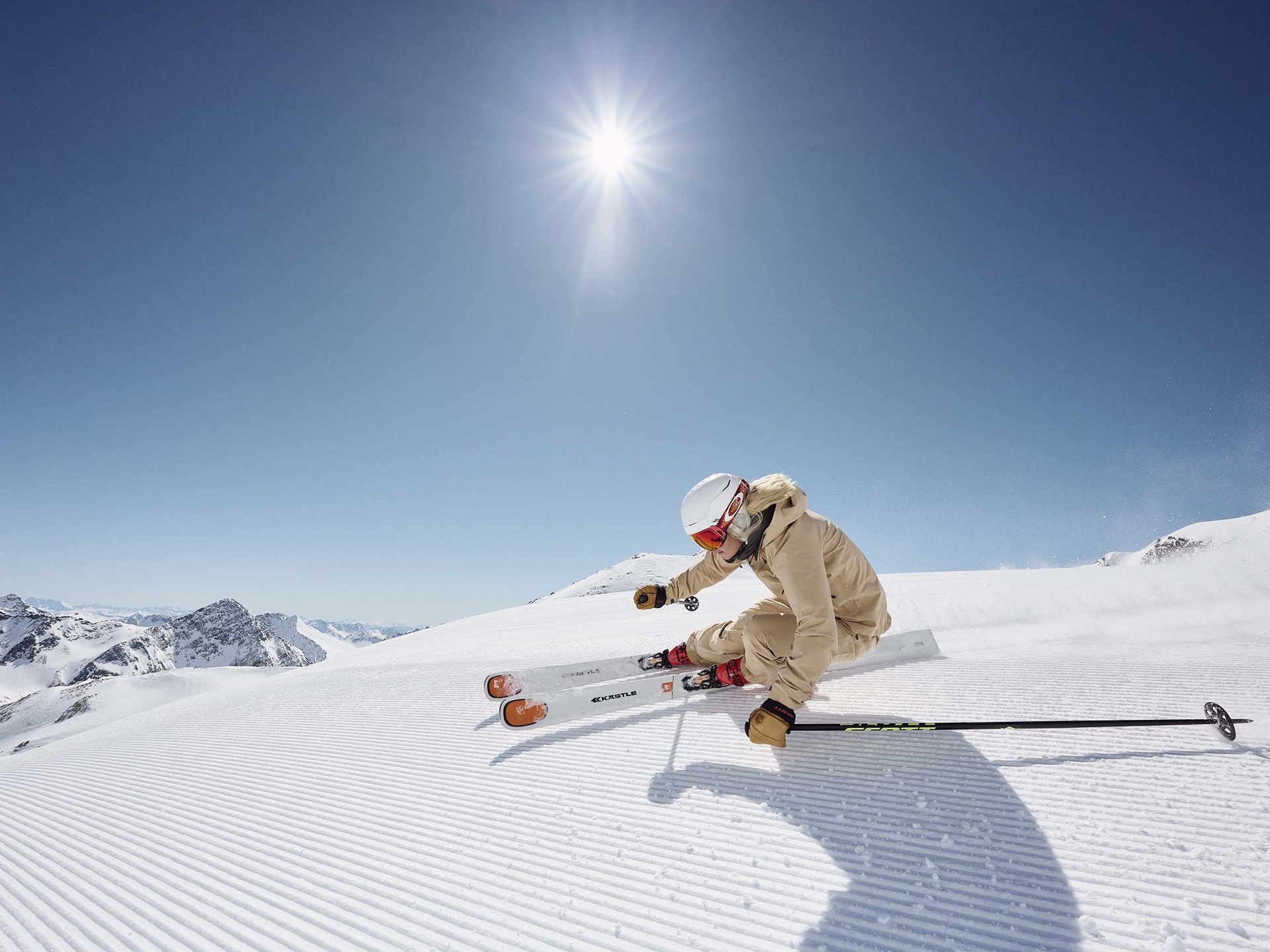 Urlaub im Stubaital im Hotel Milderer Hof Skifahrerin in Beige fährt bei sonnigem Himmel auf frisch präparierter Piste