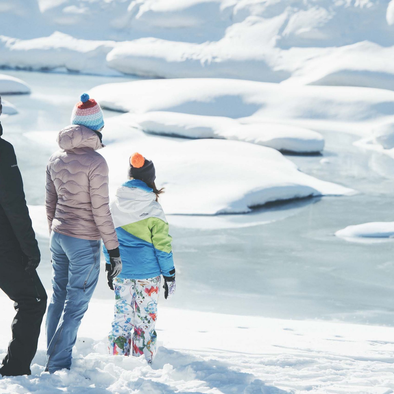 Ecco il nostro hotel: lo Stubai vi aspetta Tre persone con abiti invernali osservano un lago ghiacciato coperto di neve