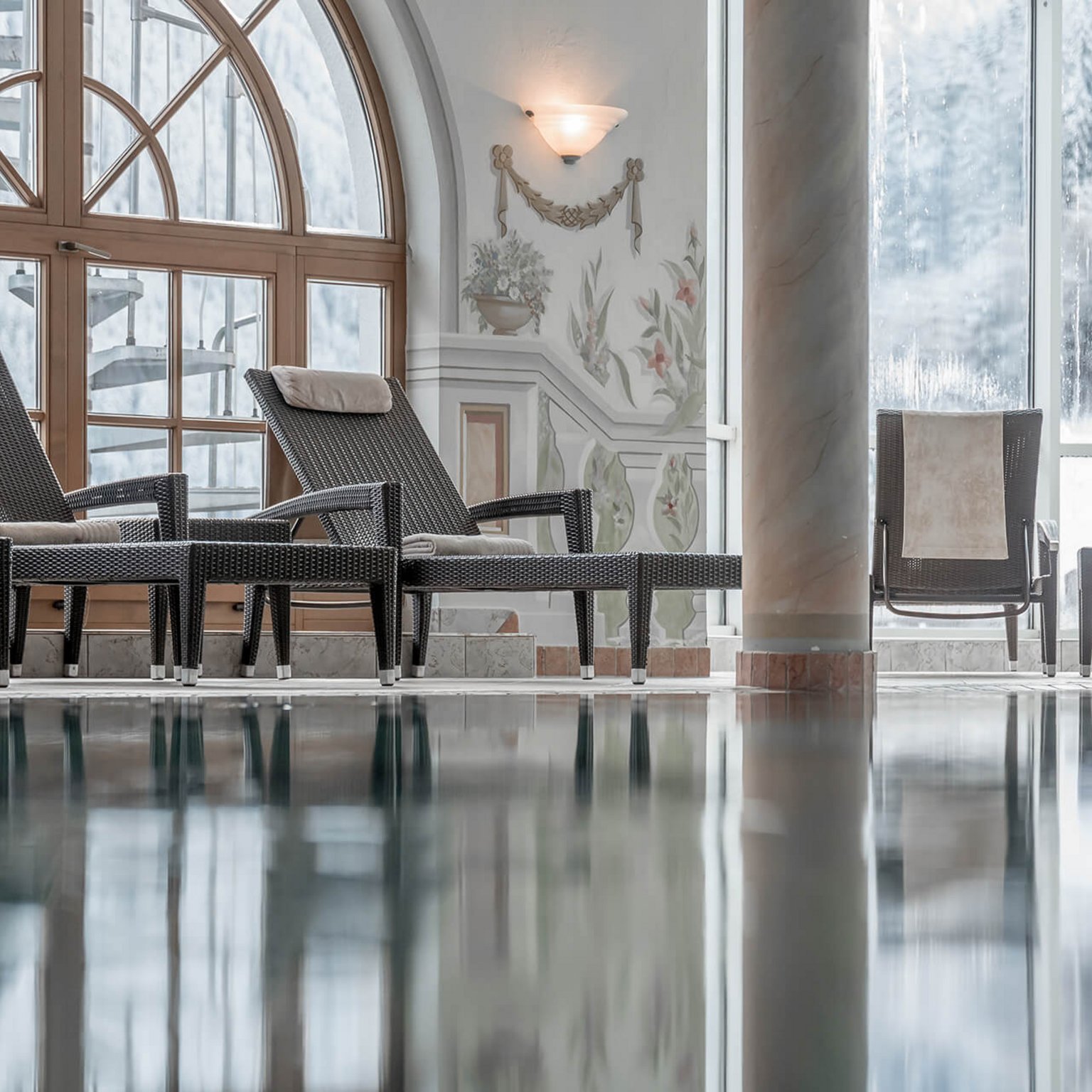 Off to the wellness hotel in Stubaital! Lounge chairs beside a calm indoor pool in an elegant spa area