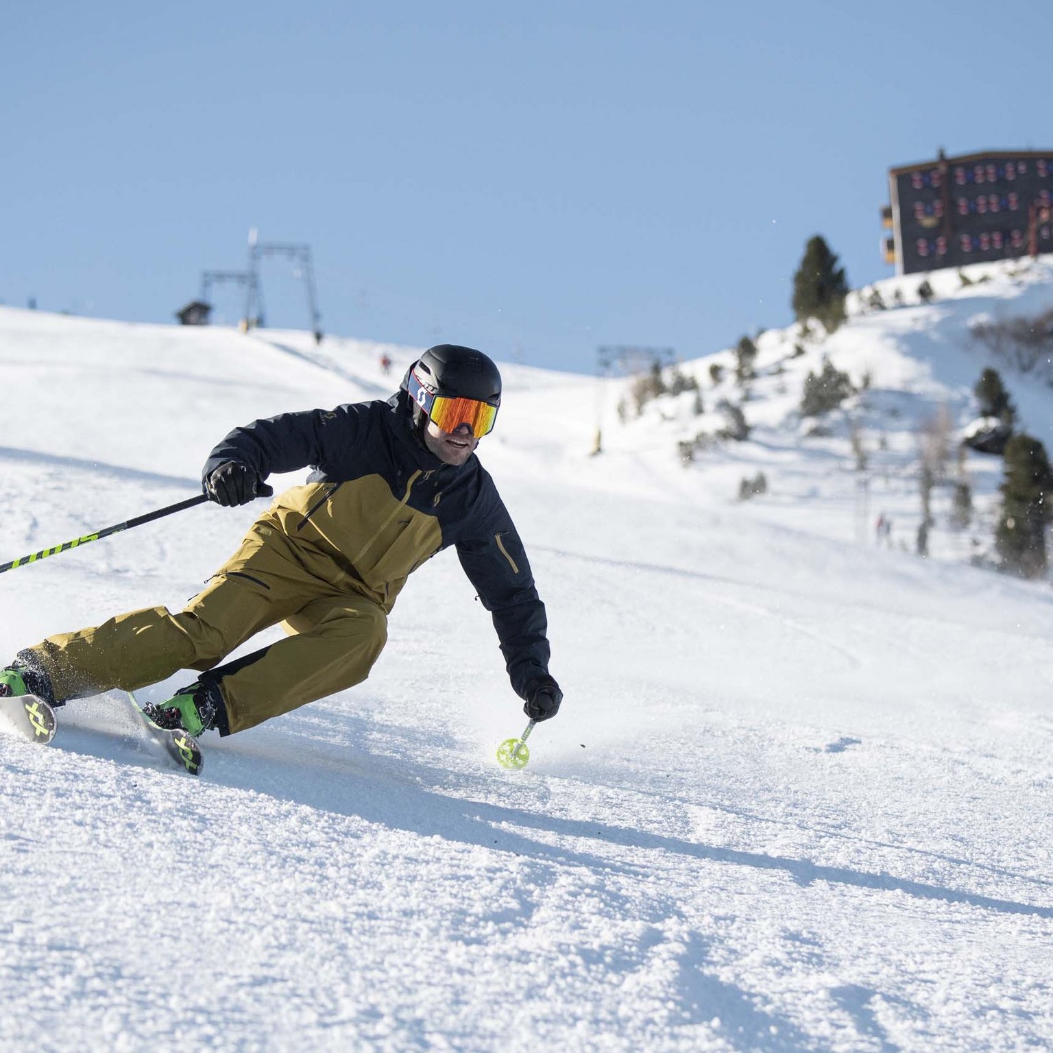 The Stubai Glacier Skier in brown jacket skiing on snowy slope under clear blue sky