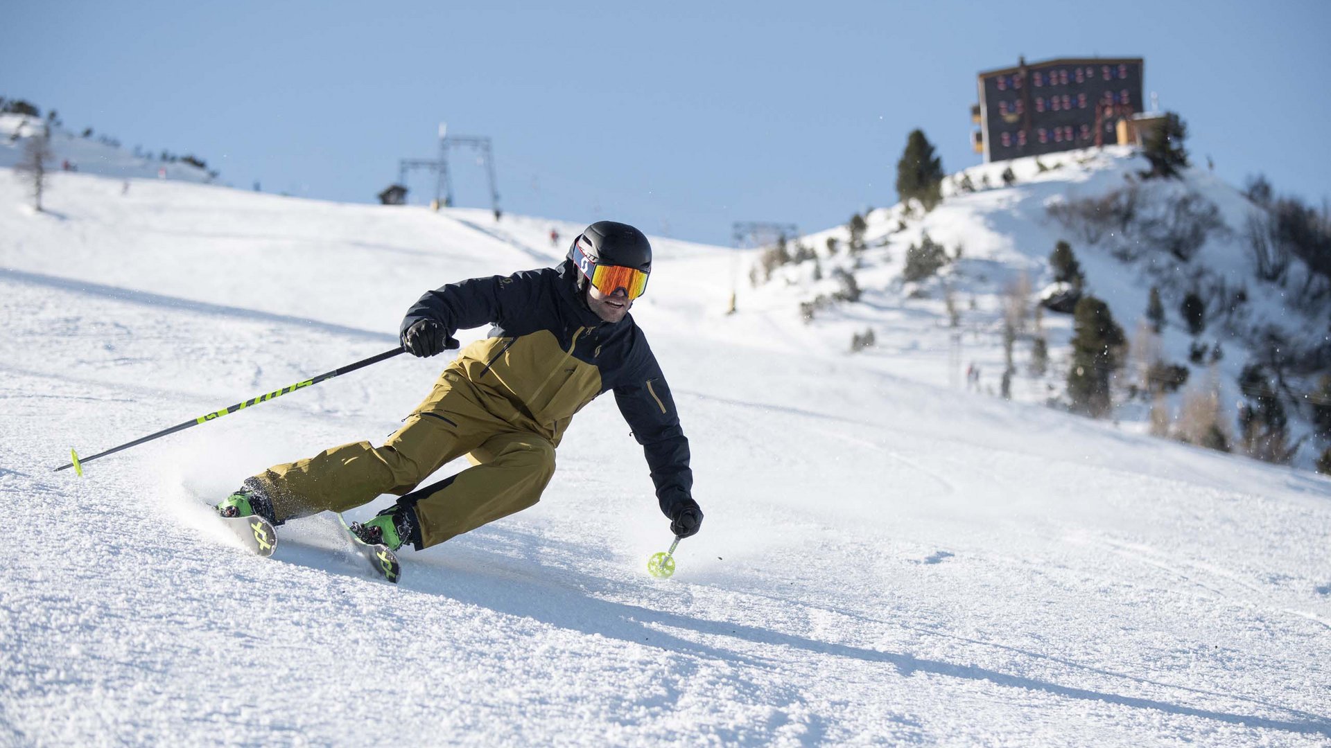 Skiing in Stubaital: offers Skier in brown jacket skiing on snowy slope under clear blue sky