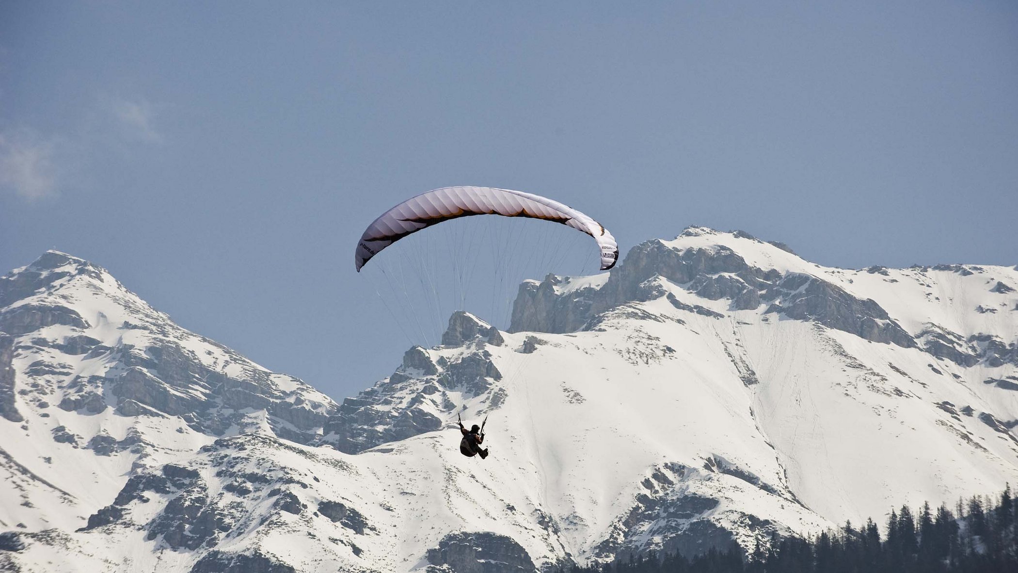Lo sci di fondo in Austria è imperdibile Parapendio vola davanti a montagne innevate sotto un cielo azzurro