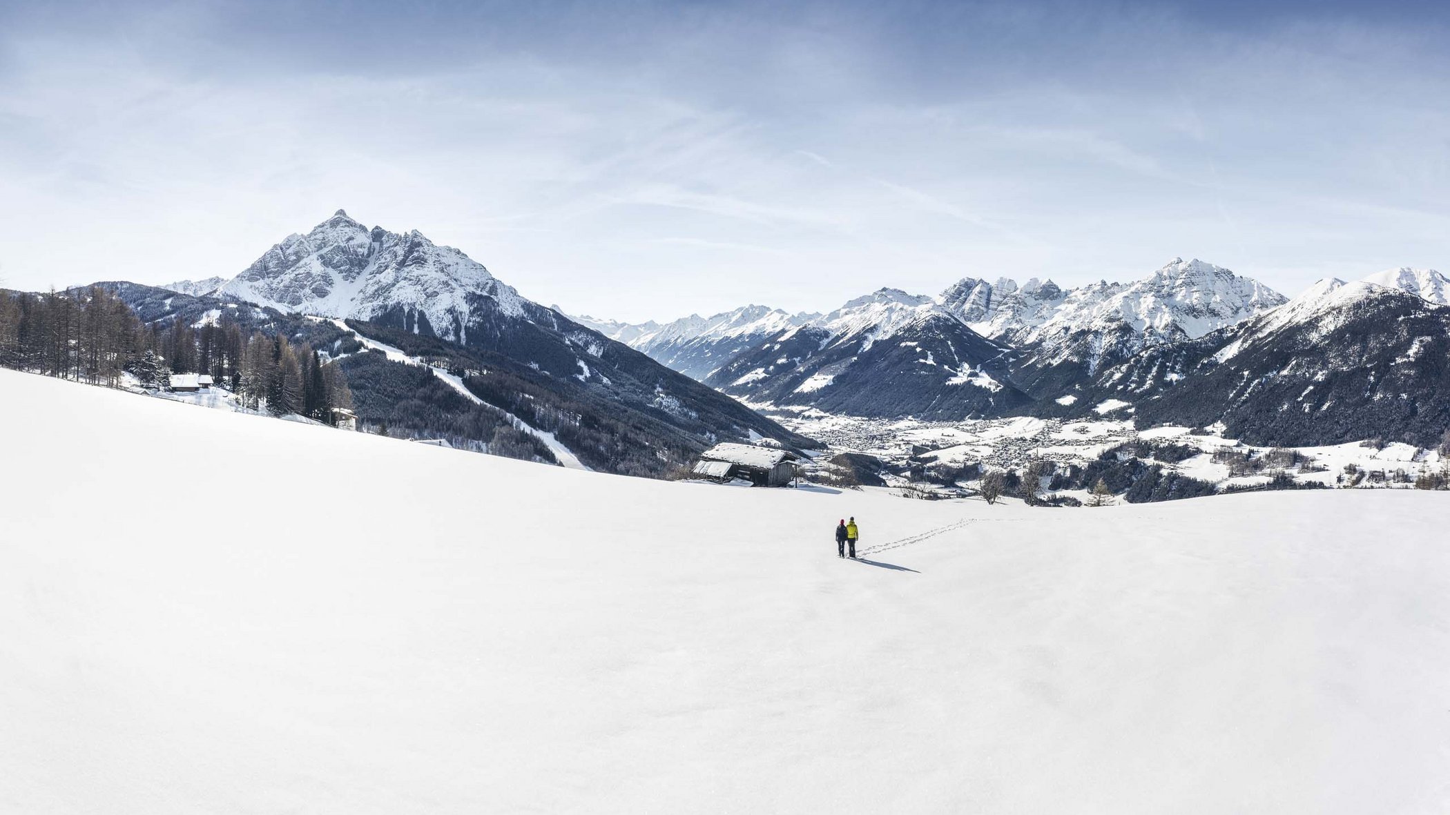 Langlaufen im Stubaital und mehr Zwei Personen gehen im weiten Schneefeld mit Bergpanorama unter blauem Himmel