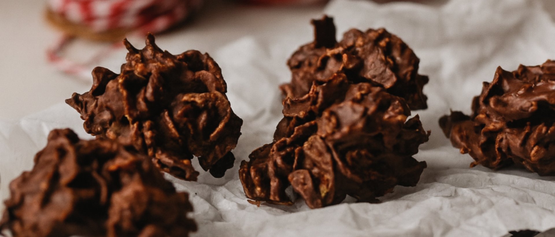 Claudias liebste Weihnachtskekse – Ein Blick in unsere Patisserie Mehrere Schokoladen-Krokantgebäcke auf Backpapier auf einem Gitter