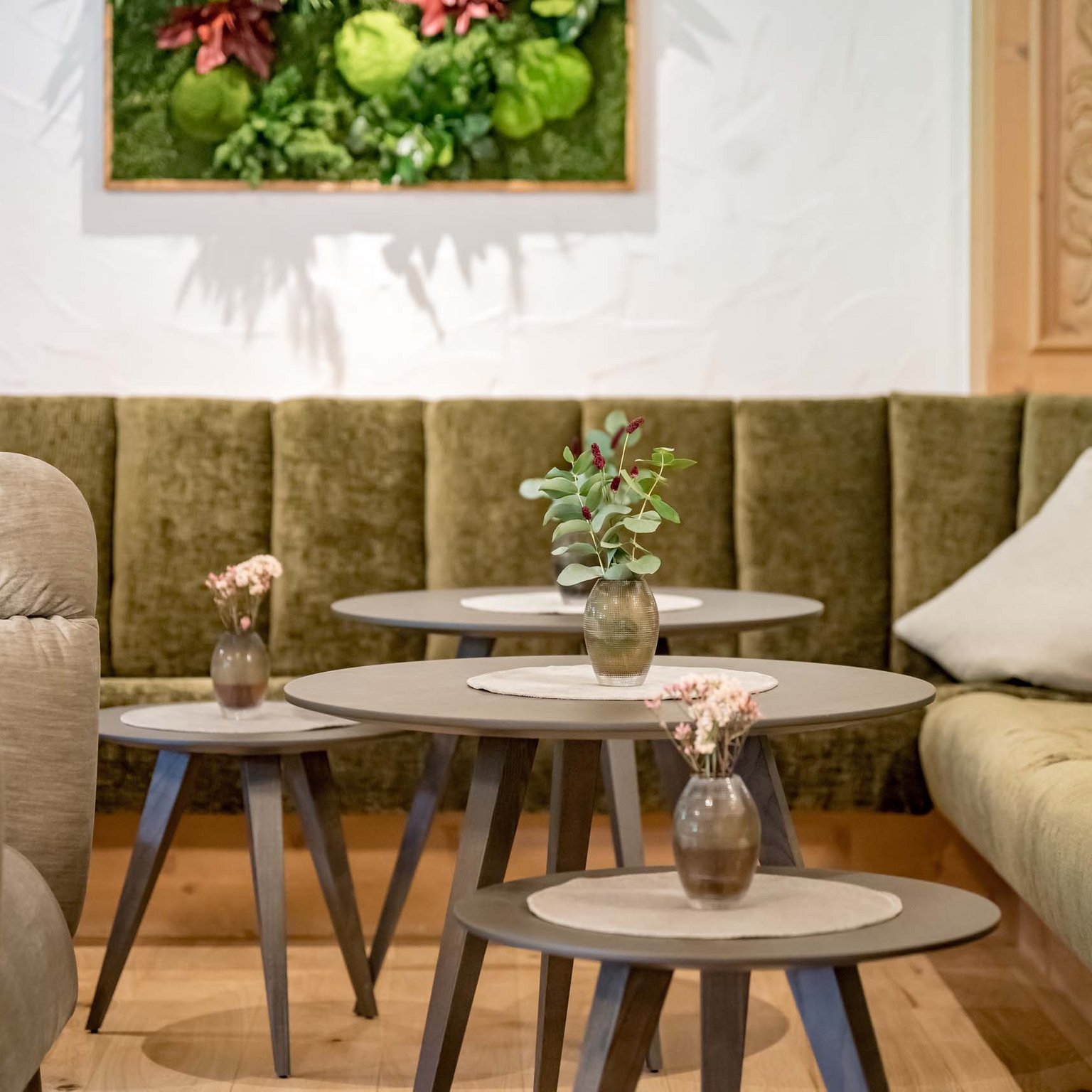 There are many hotels in Stubaital but only one Milderer Hof Cozy seating area with green upholstered bench and small tables with vases