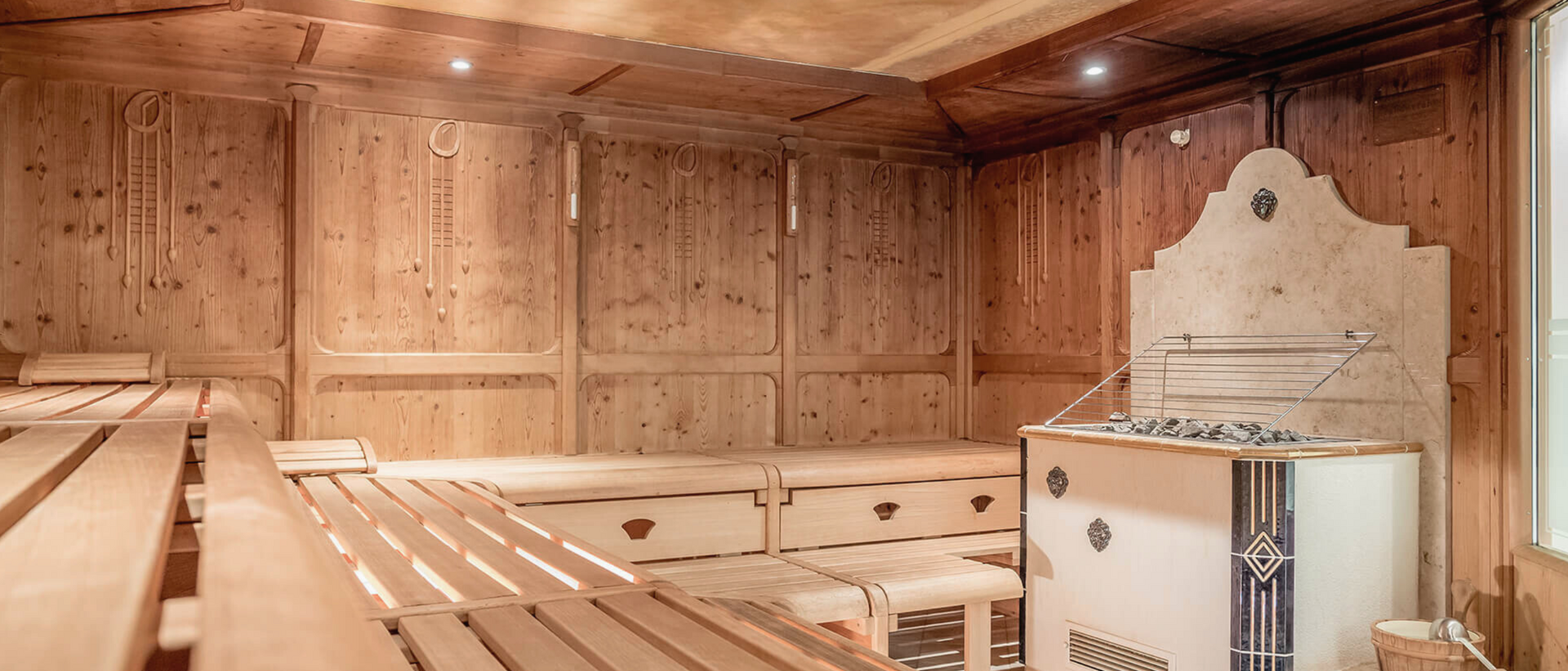 Wärme für die Seele – Ihr Sauna-Guide für den Herbst im Milderer Hof Saunaraum mit Holzbänken und Saunaofen