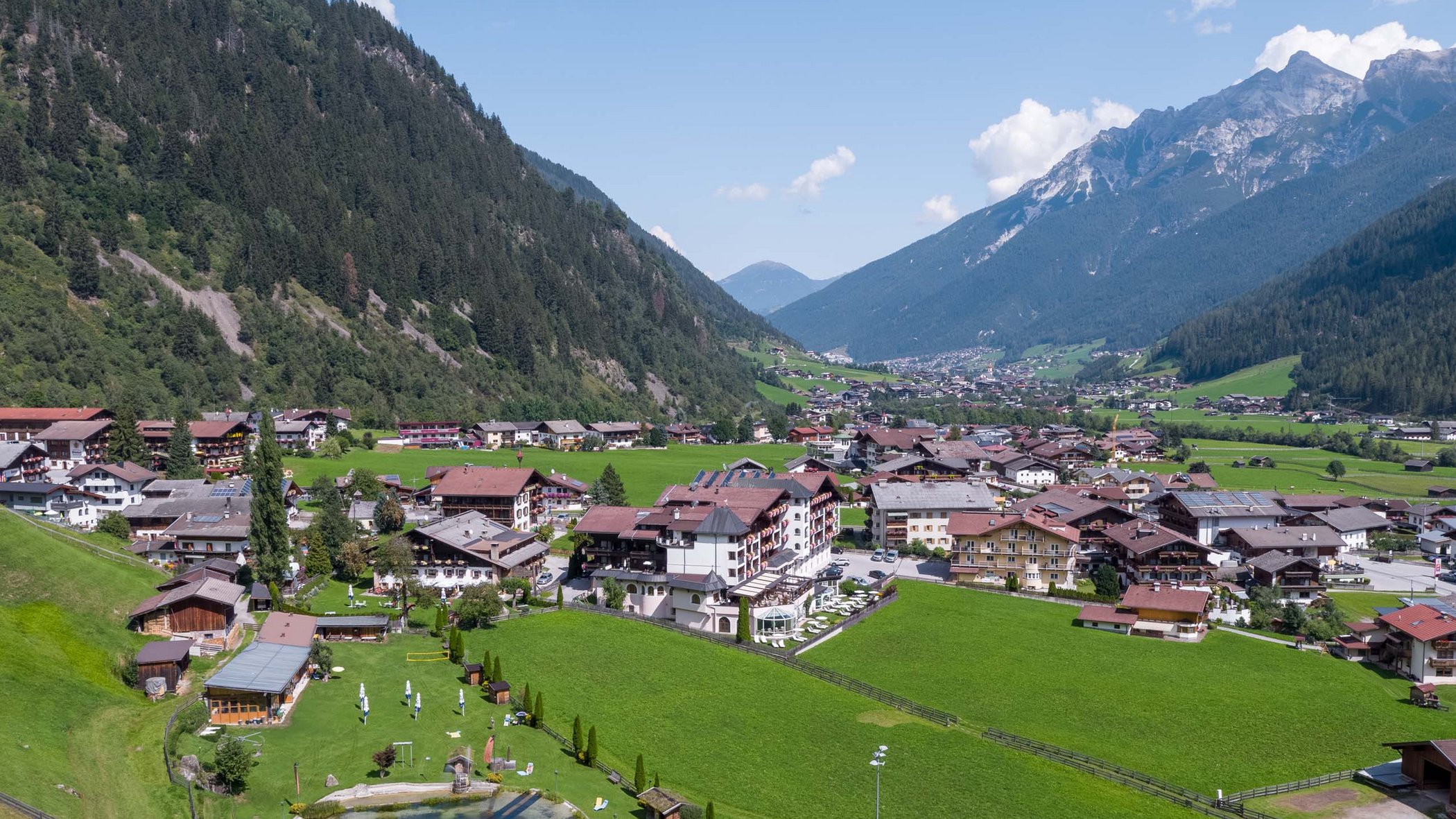 Ihre Reise zum Hotel in Neustift. Dorf in einem grünen Tal mit Bergen und kleinem See