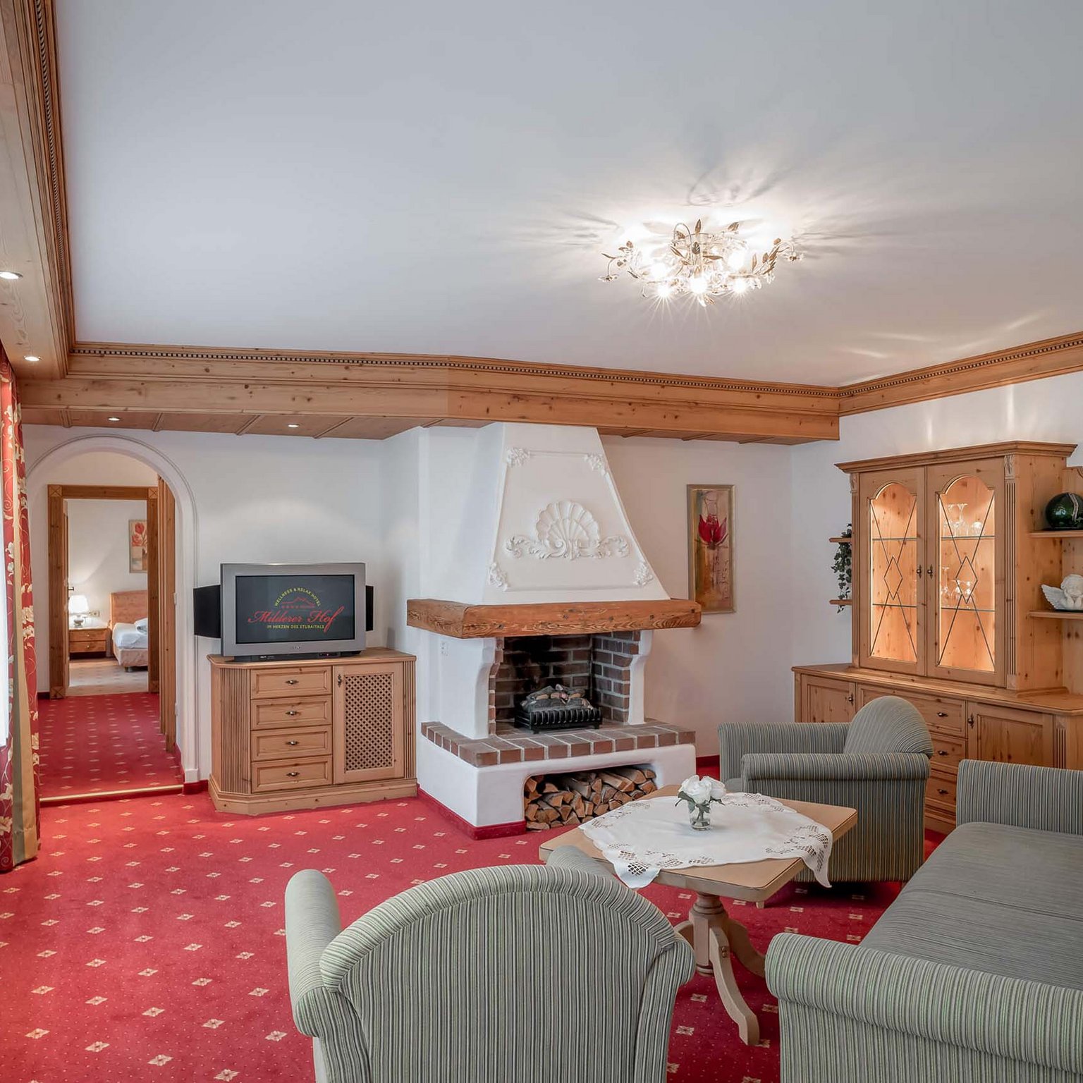 Neustift: Hotel zum Wohlfühlen Wohnzimmer mit Kamin, TV, Holzmöbeln und rotem Teppich