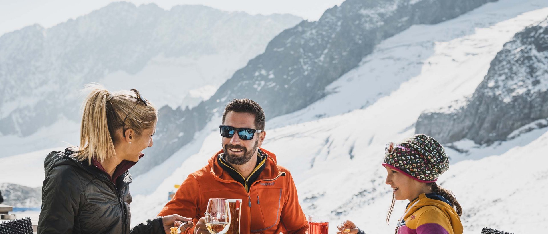 Genuss aus den Alpen Familie isst draußen in den verschneiten Bergen bei Sonnenschein