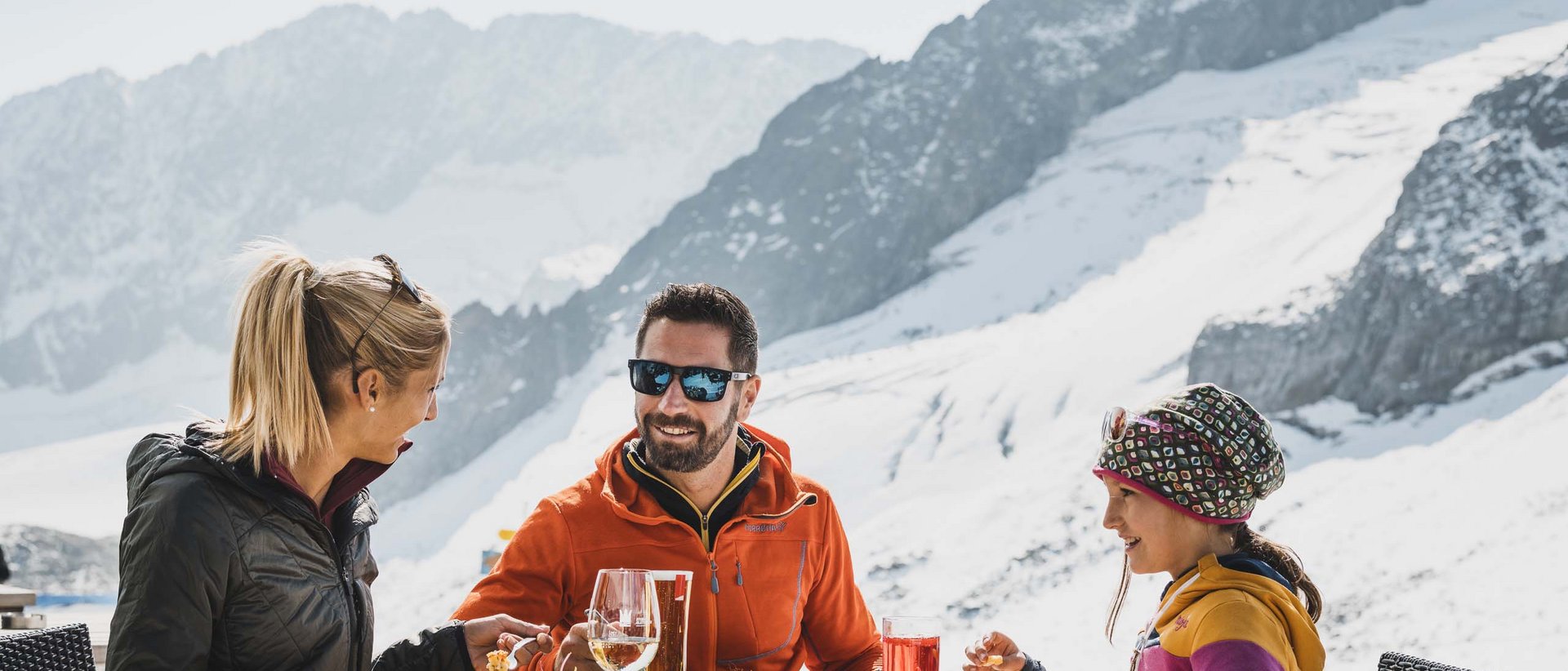 Genuss aus den Alpen Familie isst draußen in den verschneiten Bergen bei Sonnenschein