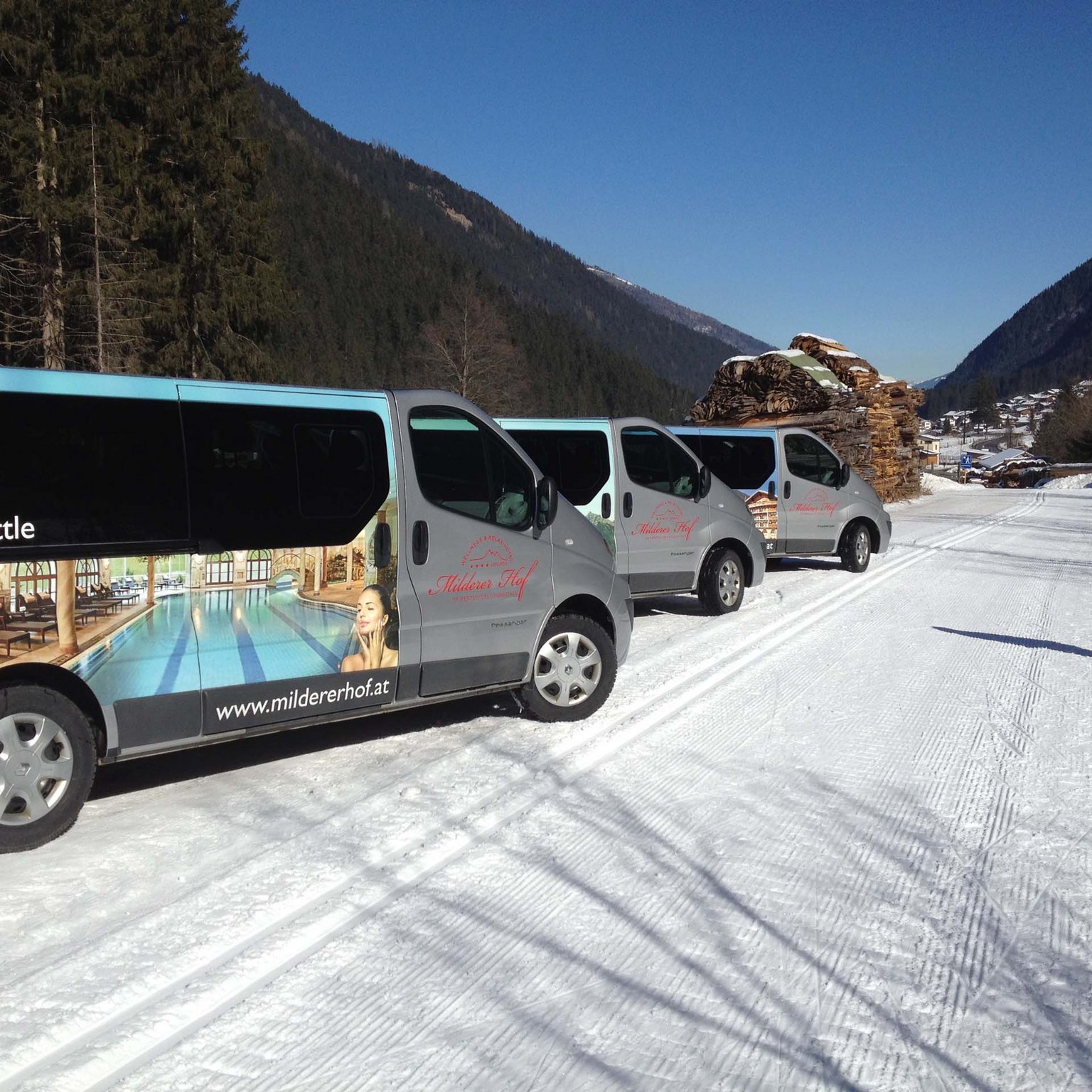 Skiing in Stubaital: offers VIP shuttle vans parked on snowy road in mountainous area with person walking