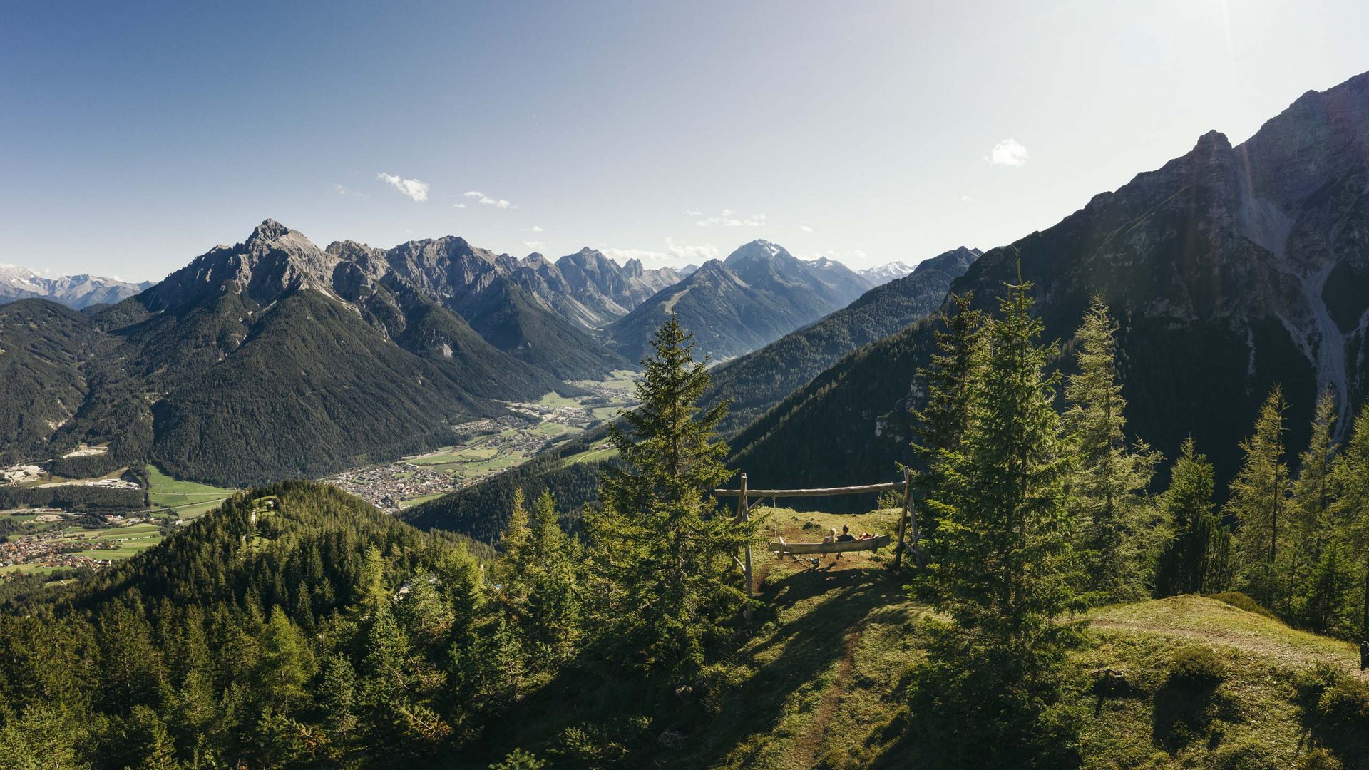 Stubaital: Hiking in summer View of mountains, forest and valley with people on a wooden swing