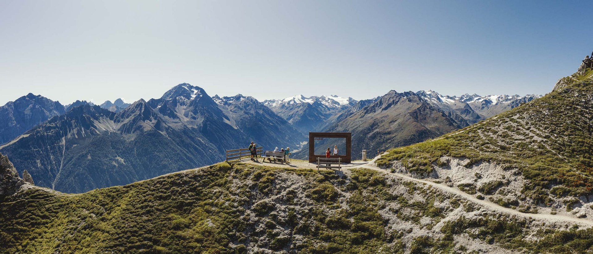 Erlebnisse und Veranstaltungen in Neustift Berglandschaft mit Aussichtspunkt und Menschen auf einem sonnigen Gipfel