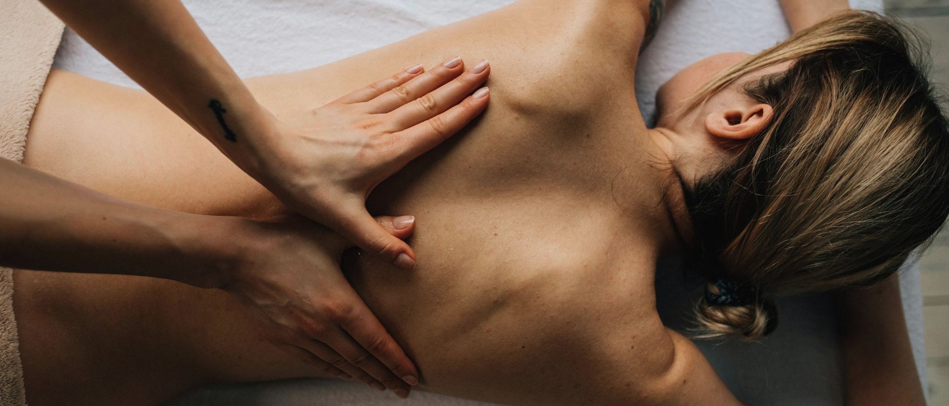 Drei Rituale. Eine Essenz: Wellness im Milderer Hof Frau erhält Rückenmassage auf Massagetisch in Spa-Umgebung