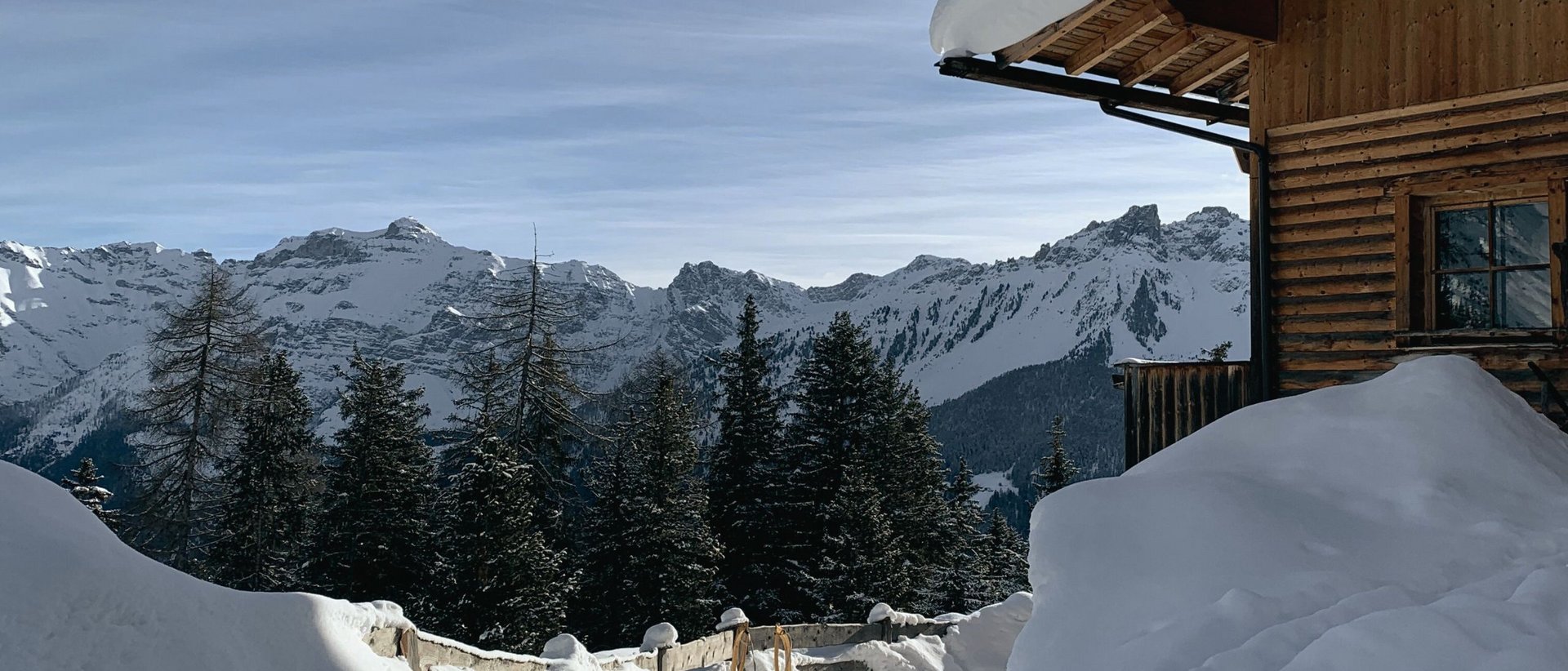 Winterzauber im Stubaital: Unsere liebste Winterwanderung zur Brandstattalm Verschneiter Weg mit Schlitten vor einer Holzhütte in den Bergen