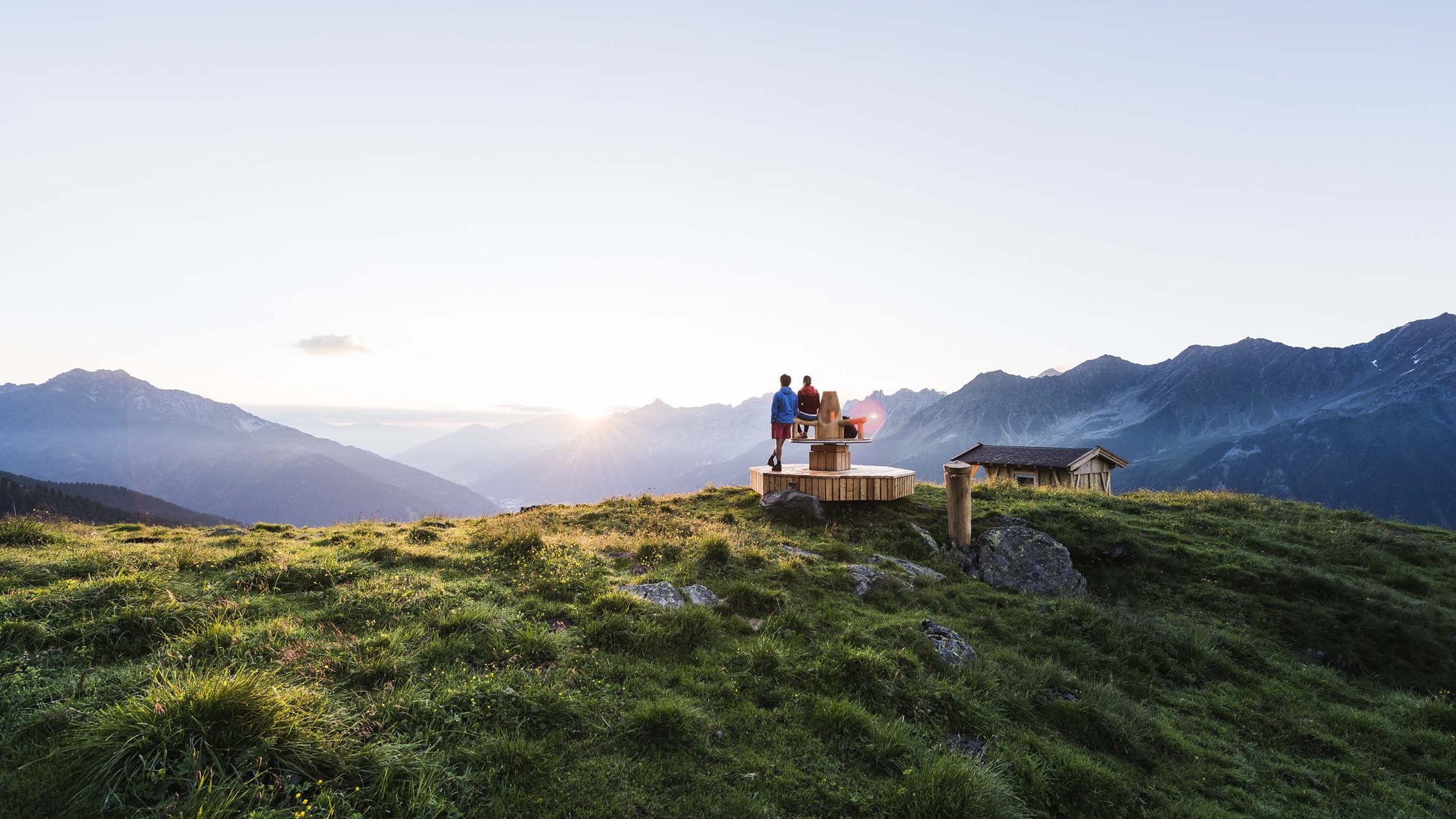 Stubaital: activities in summer Two people on a wooden platform in the mountains at sunset