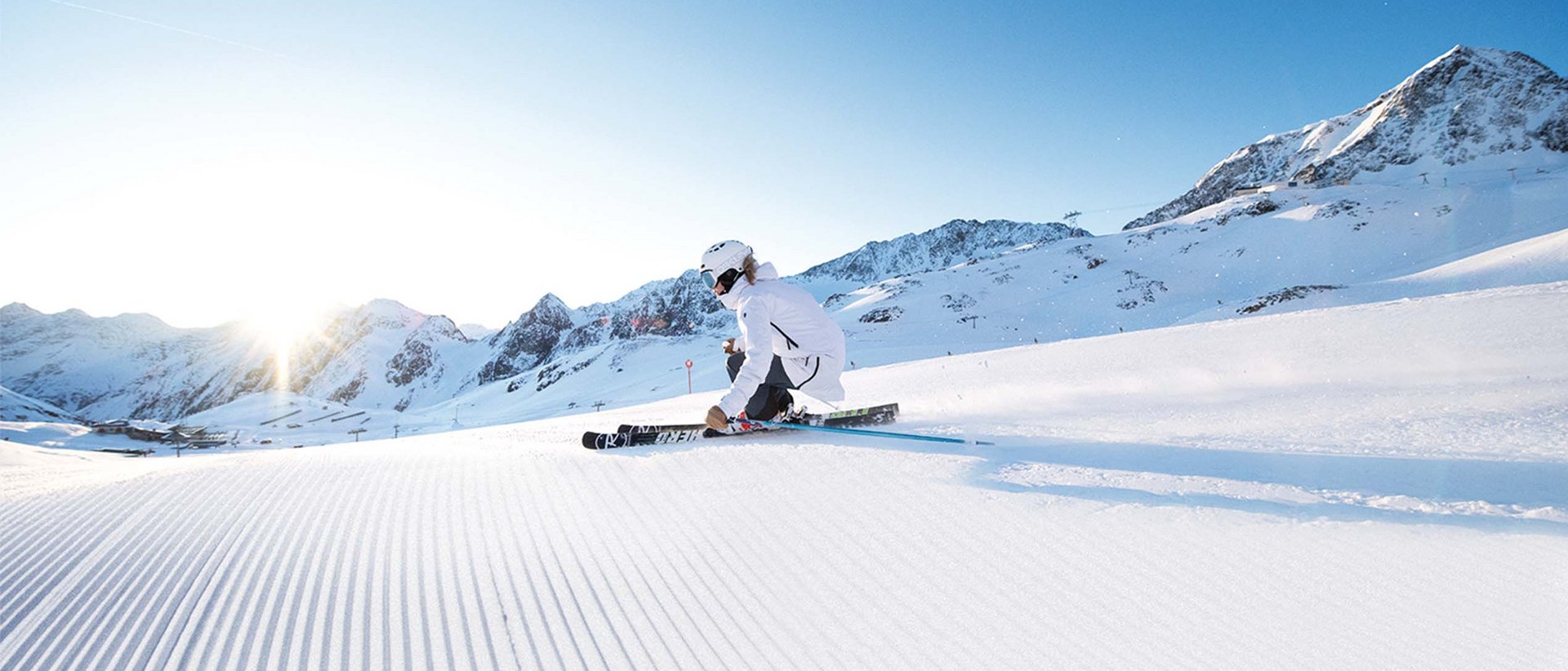 Wintererlebnisse in der Gletscherwelt Skifahrer in weißer Kleidung fährt an sonnigem Tag auf frischem Schnee