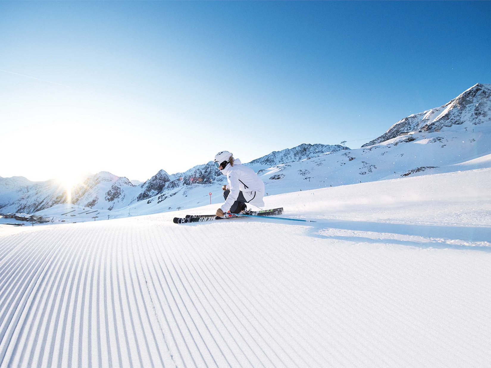 Stubaital: our hotel with a pool Skier in white outfit skiing on fresh snow on a sunny day