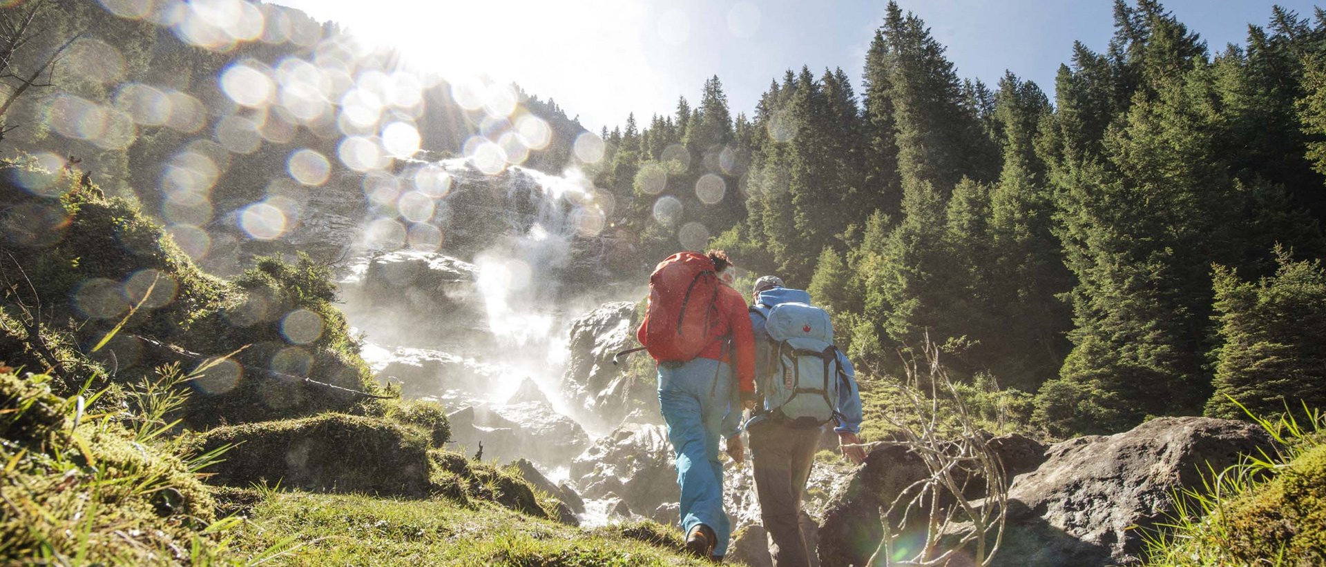 Sommernachtstraum im Stubaital Zwei Wanderer mit Rucksäcken steigen bei sonnigem Wetter zu einem Wasserfall auf