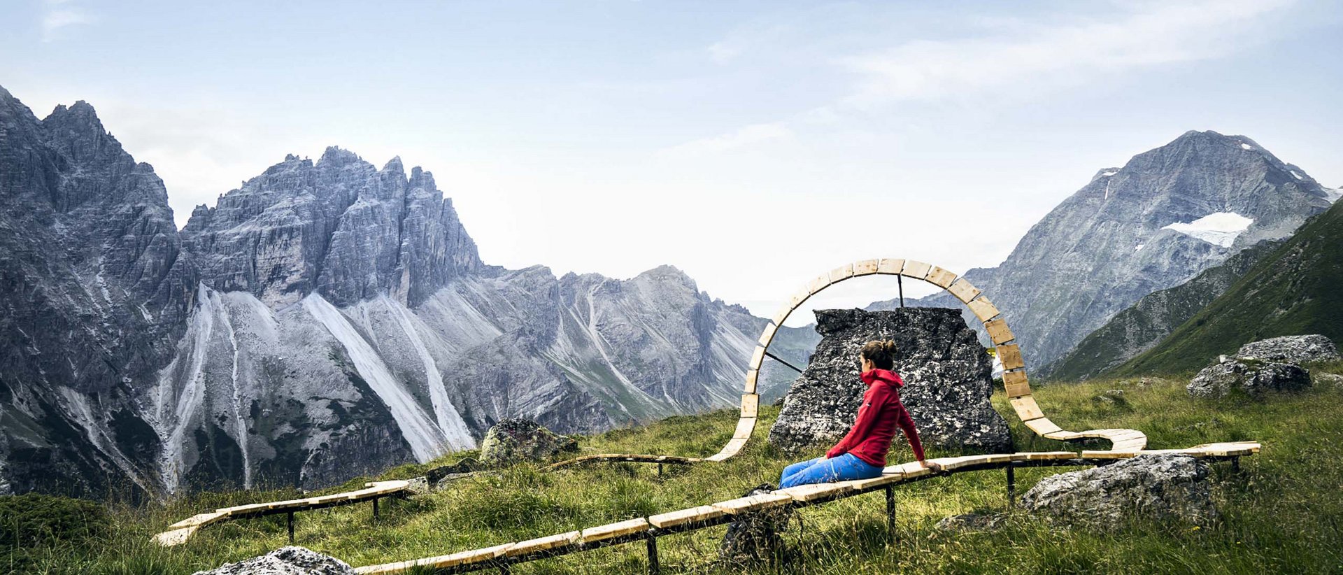 Urlaub auf Stubaier Art Frau in roter Jacke sitzt auf Bank in den Bergen mit Panoramablick