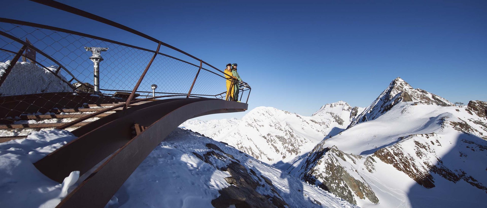 Das Bergpanorama in vollen Zügen genießen Zwei Personen auf Aussichtsplattform mit Blick auf schneebedeckte Berge