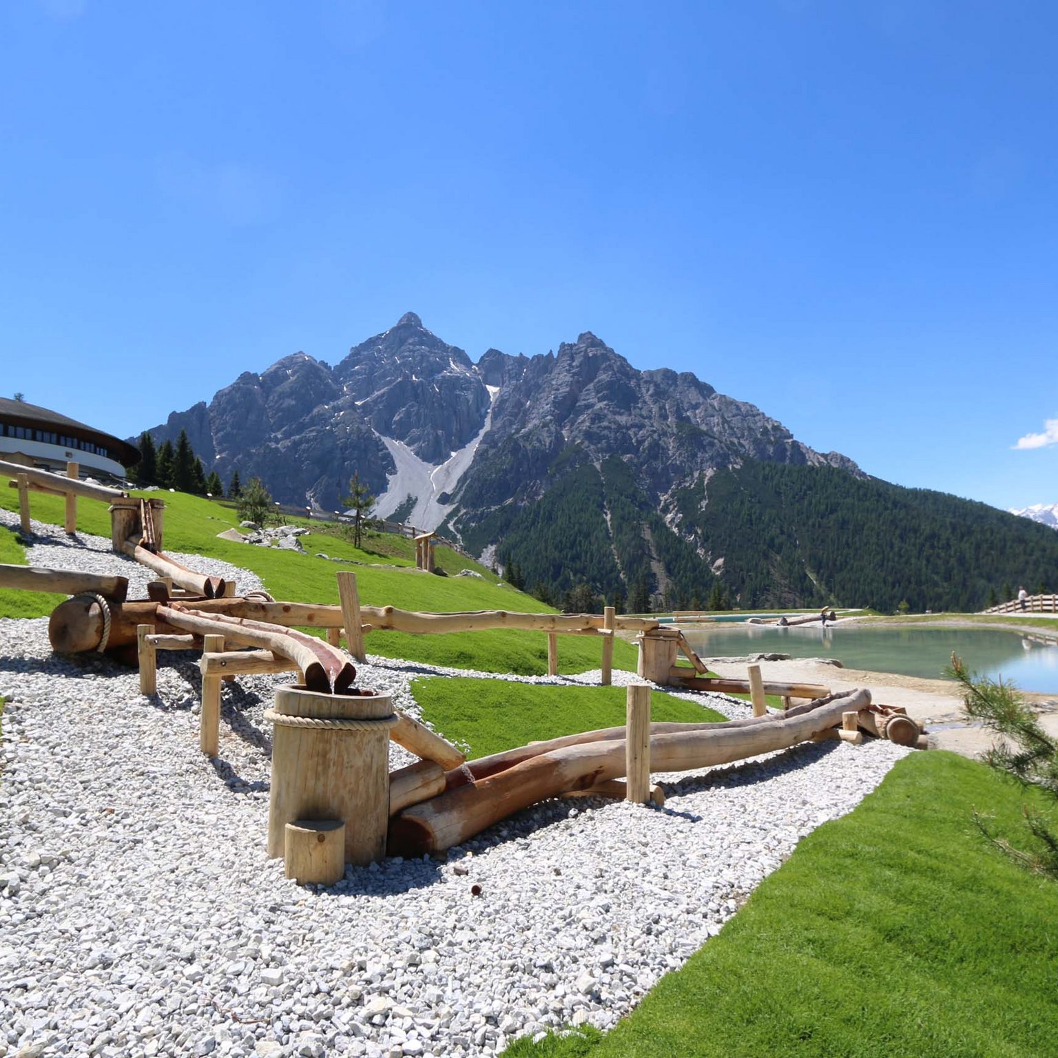 Stubaital: activities in summer Wooden water channel on white gravel with mountain backdrop and blue sky