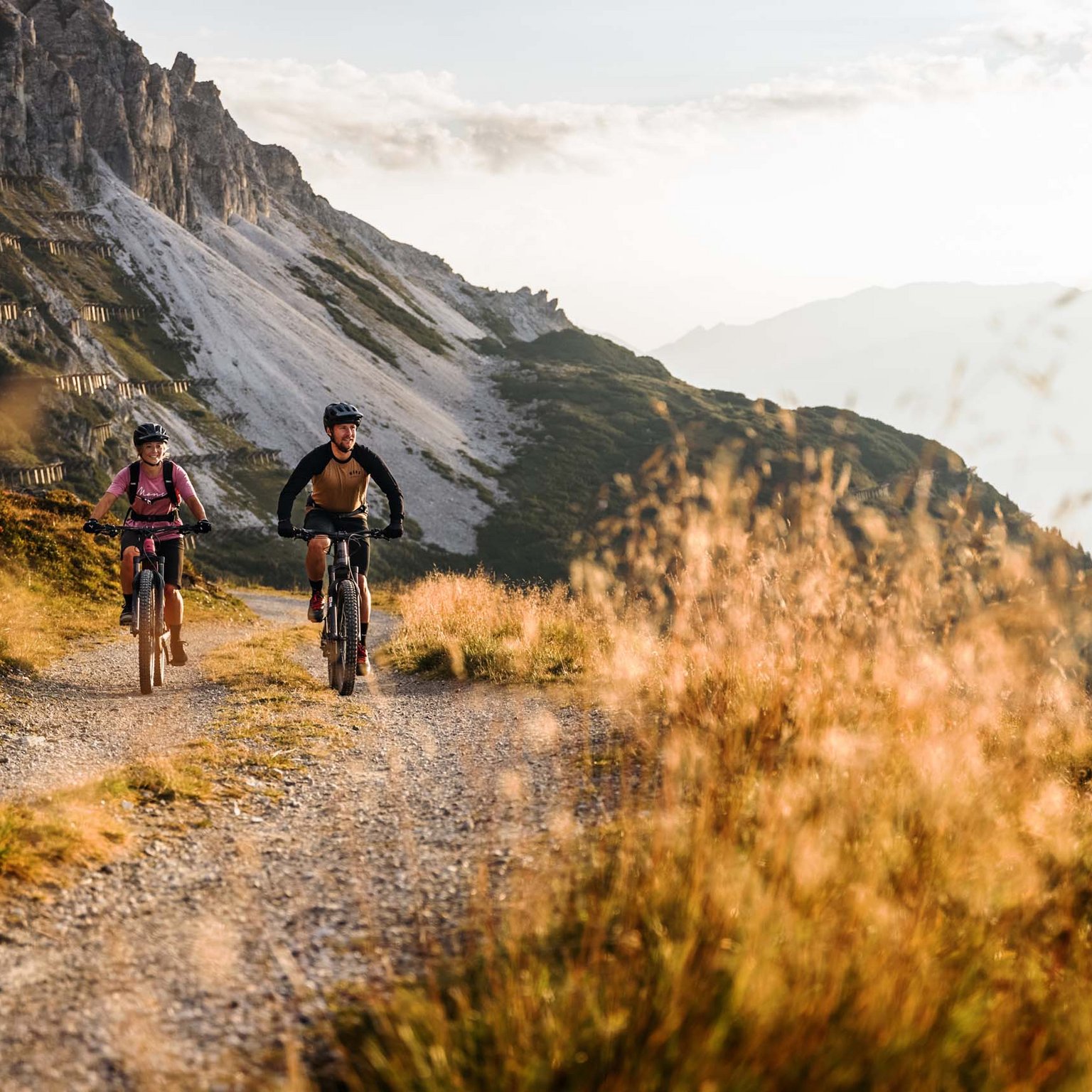 Hotel in Stubaital near Fulpmes Two mountain bikers riding on a rocky mountain trail at sunset