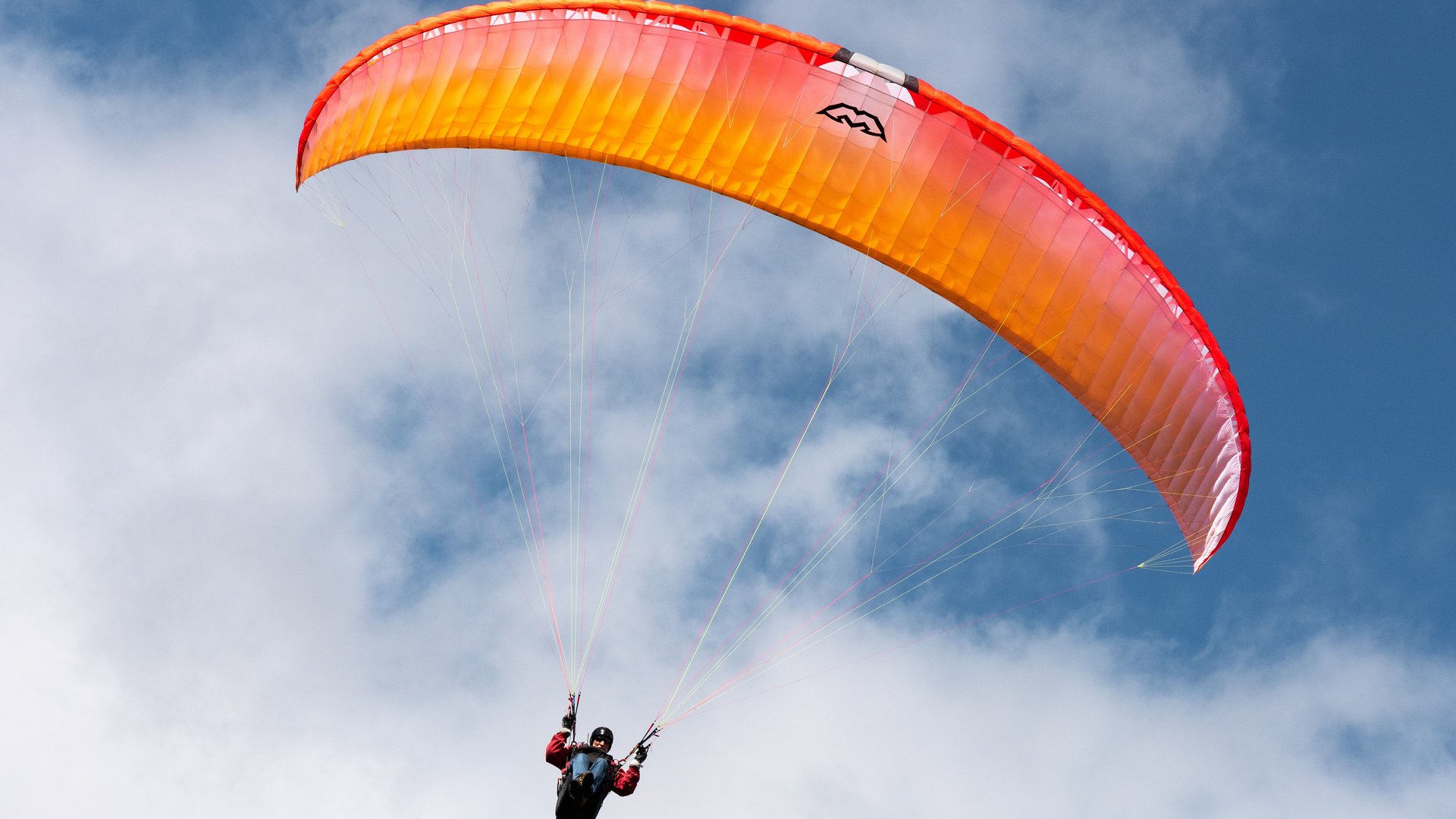 Things to do in Stubaital Person paragliding with orange-red wing in the sky