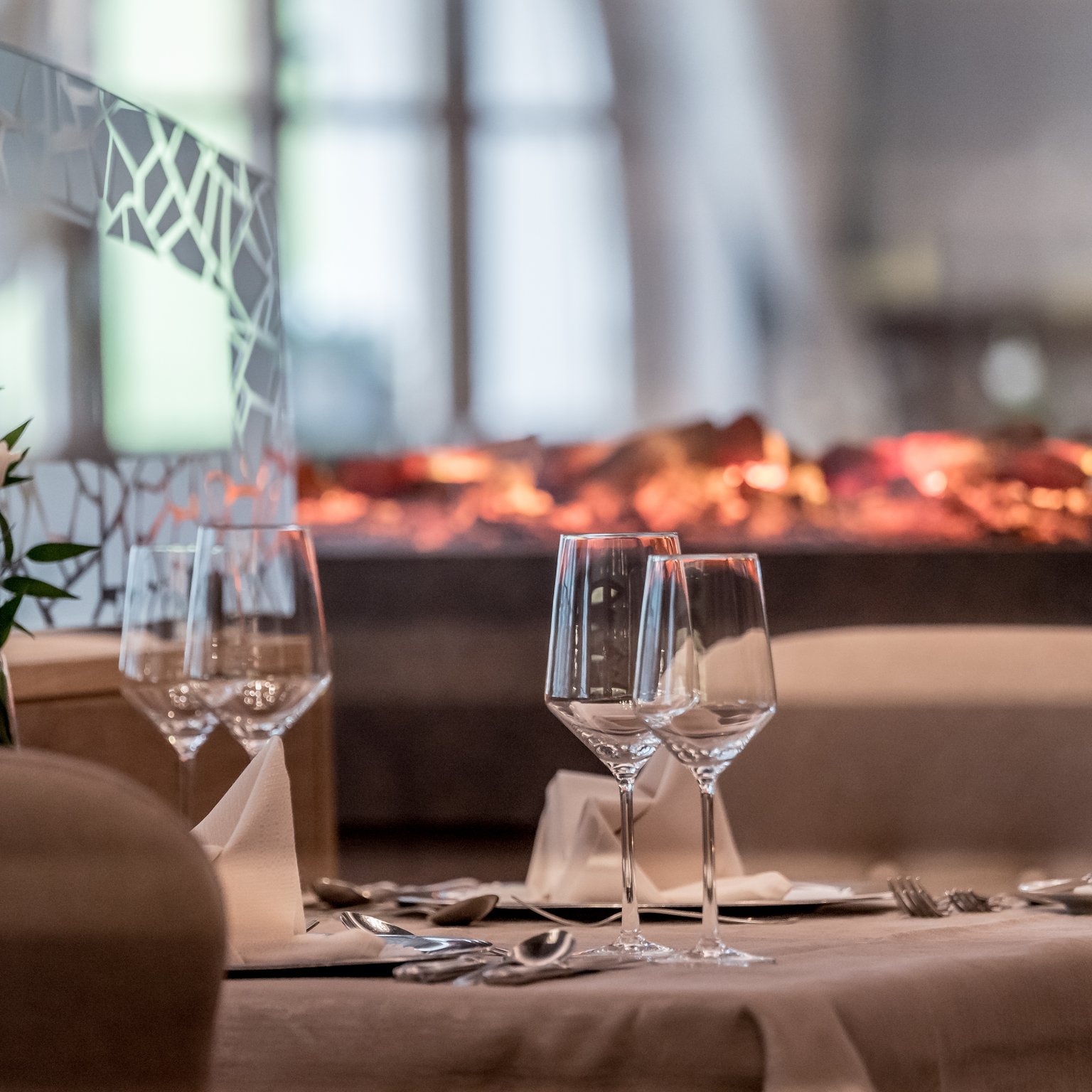 Neustift: Hotel zum Wohlfühlen Eleganter Esstisch mit Weingläsern und Dekoration vor einem Kaminfeuer
