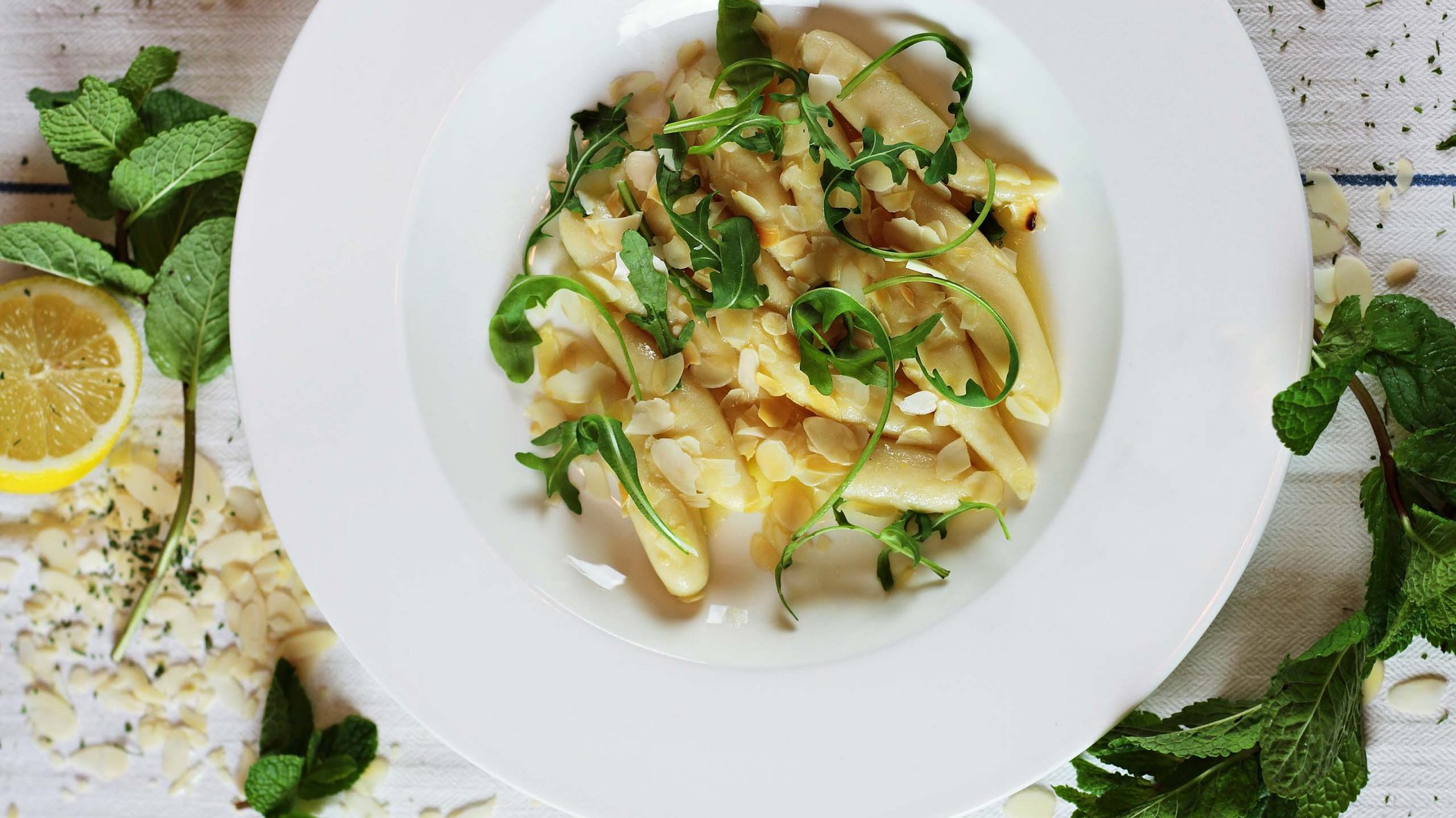 Hotels/Tyrol: 4-star superior holidays Plate of potato gnocchi with almonds and arugula, surrounded by mint leaves and lemon slice