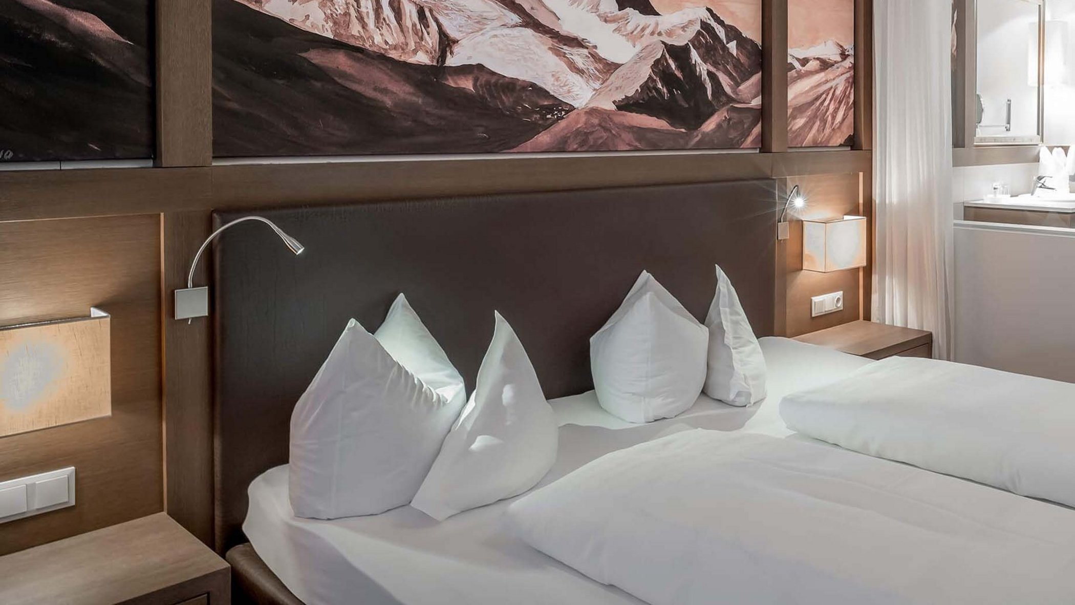 Your hotel in Neustift in Stubaital Hotel room with double bed, mountain painting above headboard, and open bathroom