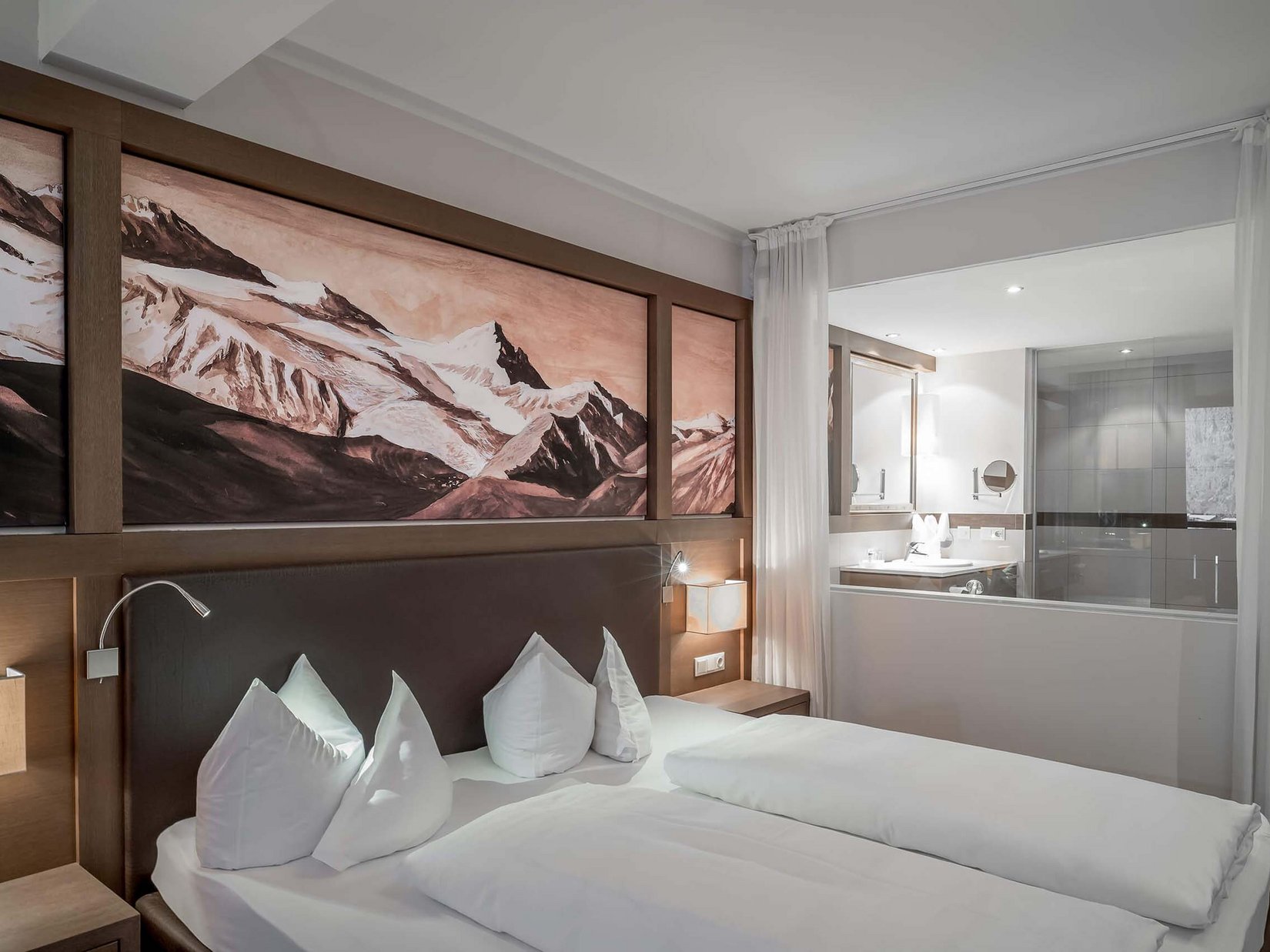 Stubaital: our hotel with a pool Hotel room with double bed, mountain painting above headboard, and open bathroom