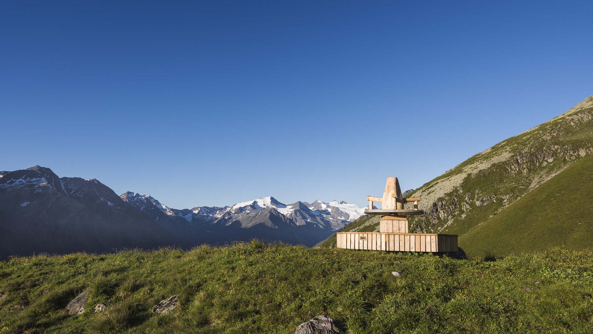 Il Ghiacciaio dello Stubai Panchina in legno su prato verde in montagna con cime innevate sullo sfondo