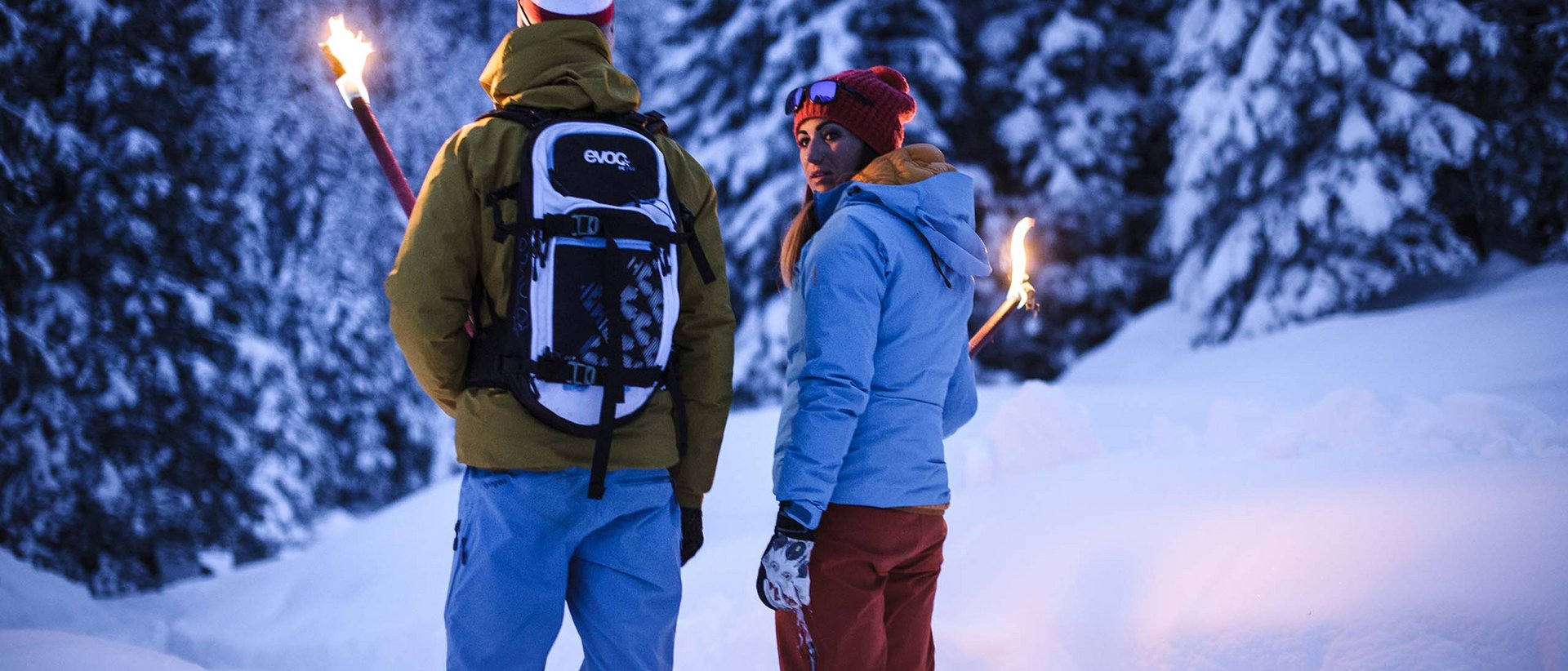 Alle Jahre wieder Zwei Personen mit Fackeln in einem verschneiten Wald bei Dämmerung