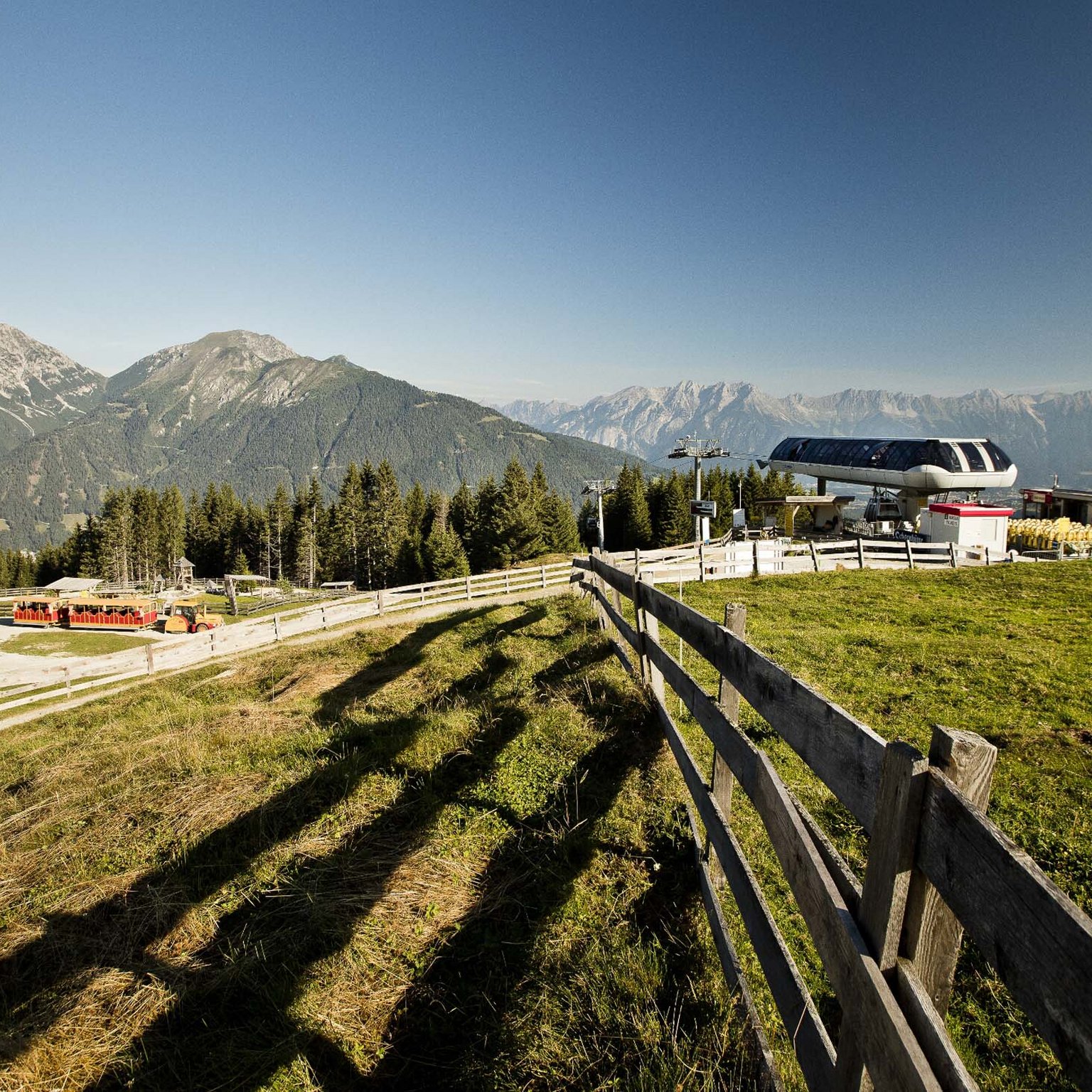 Scoprite la Stubai Super Card e i suoi vantaggi Paesaggio montano con stazione seggiovia e recinzione in una valle soleggiata